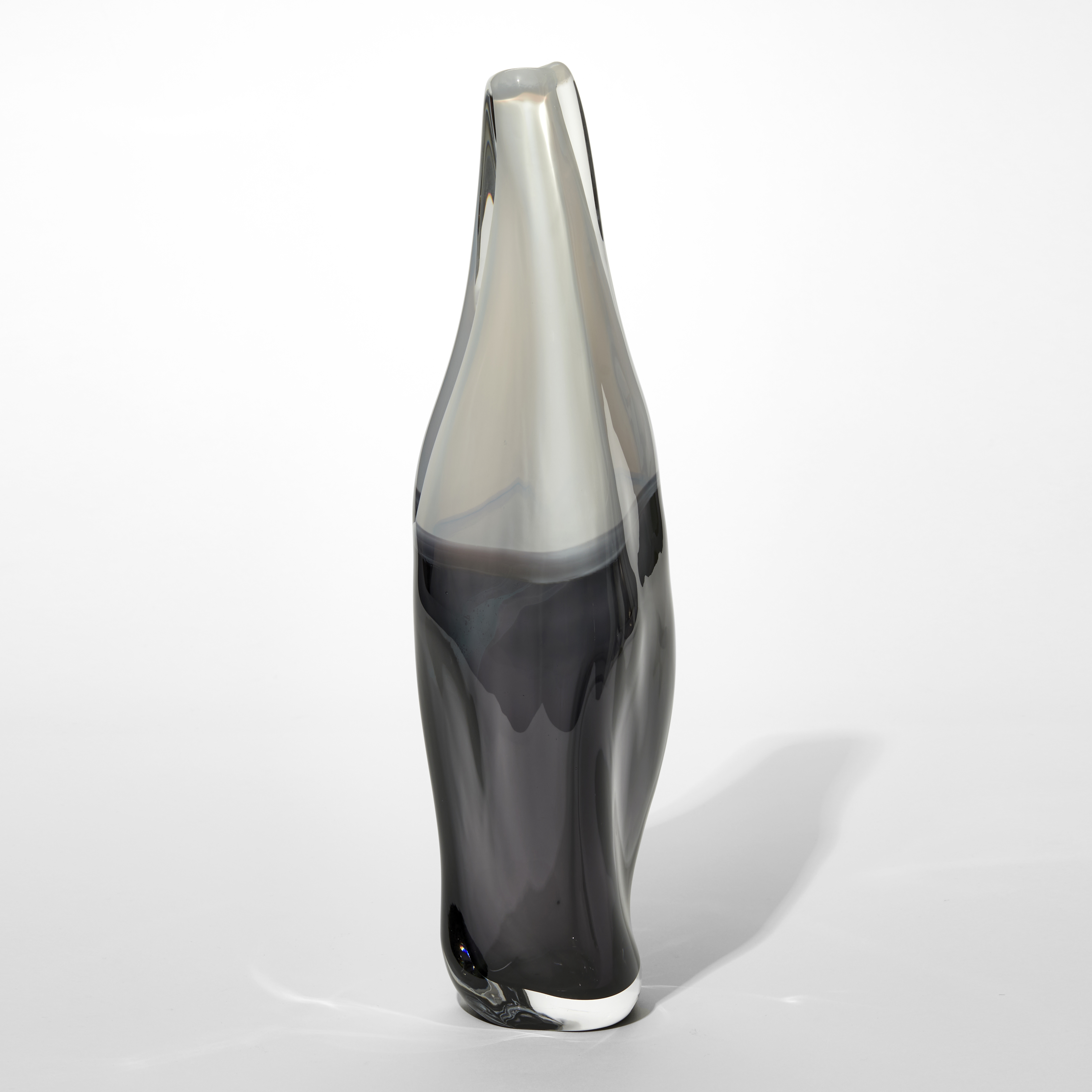 soft bottle shaped vase with tapering neck and flared foot with the bottom half in smokey black and the top half in opaque white hand made from glass