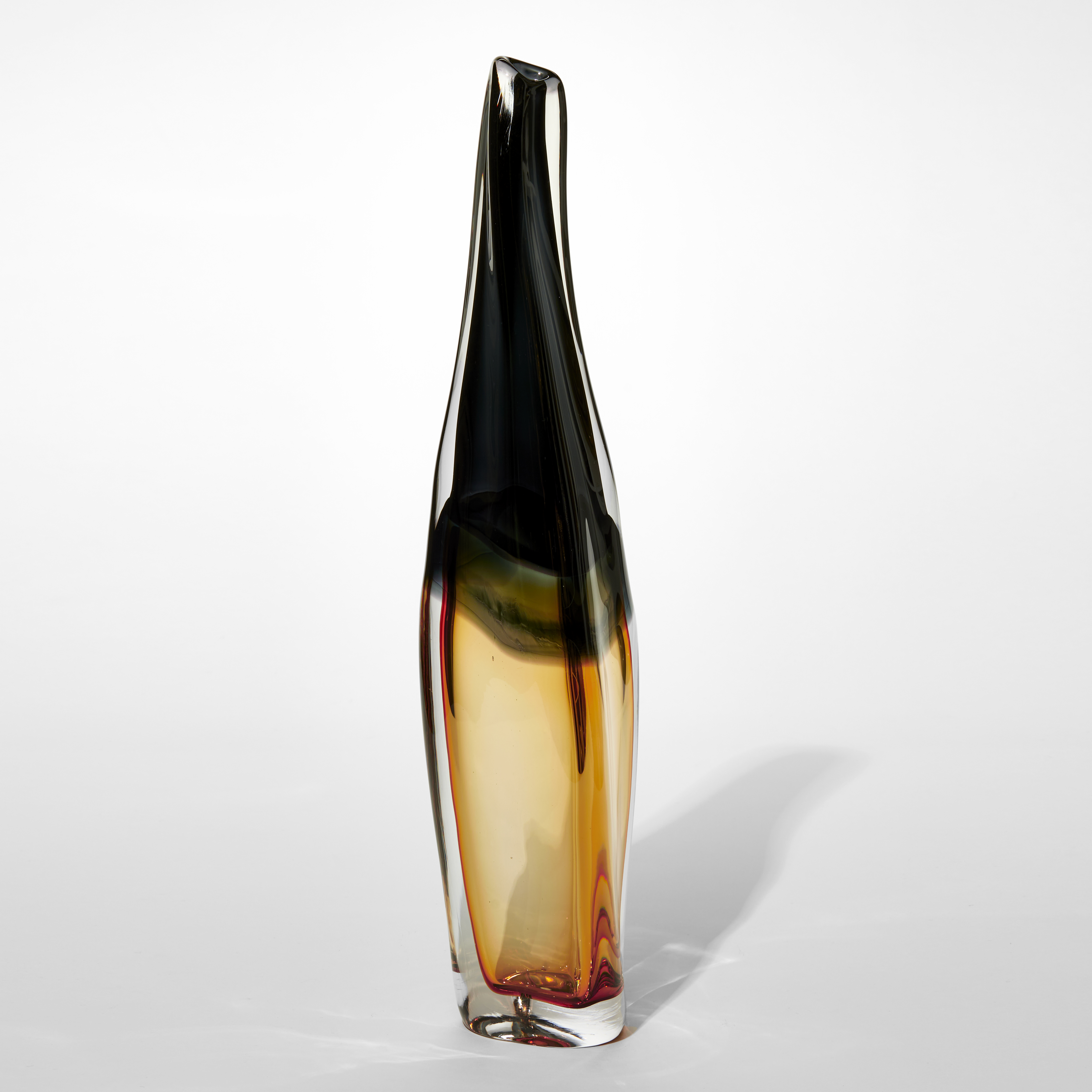 tall vase with narrow tapering neck with organic fluid outline with the top half in dense black the bottom in soft amber all encased in a clear layer hand made from glass