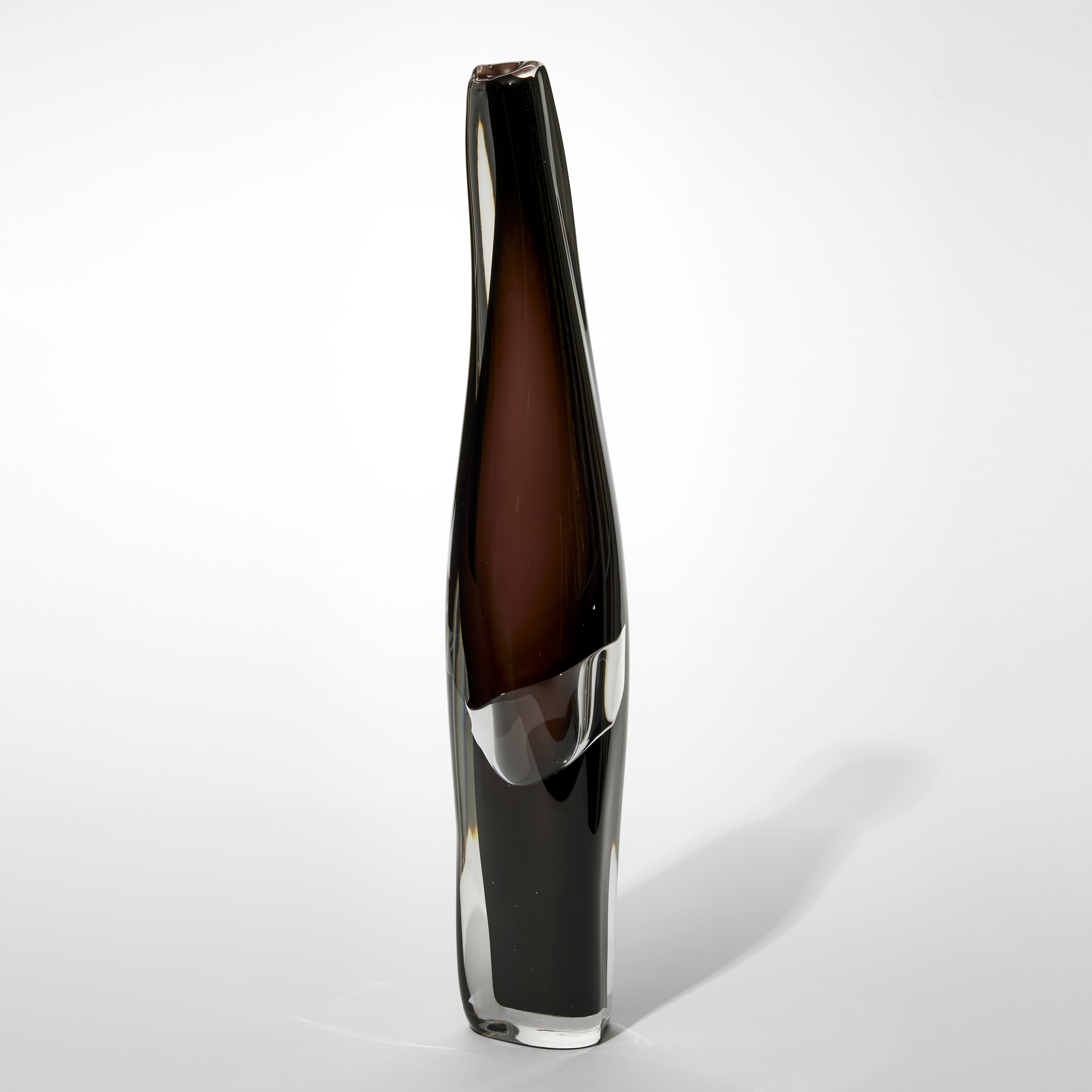 tall tapering soft sculptural vessel with fluid silhouette and dark brown interior with an outer layer in clear and an organic bubble round the waist a third of the way up from the bottom hand made from glass