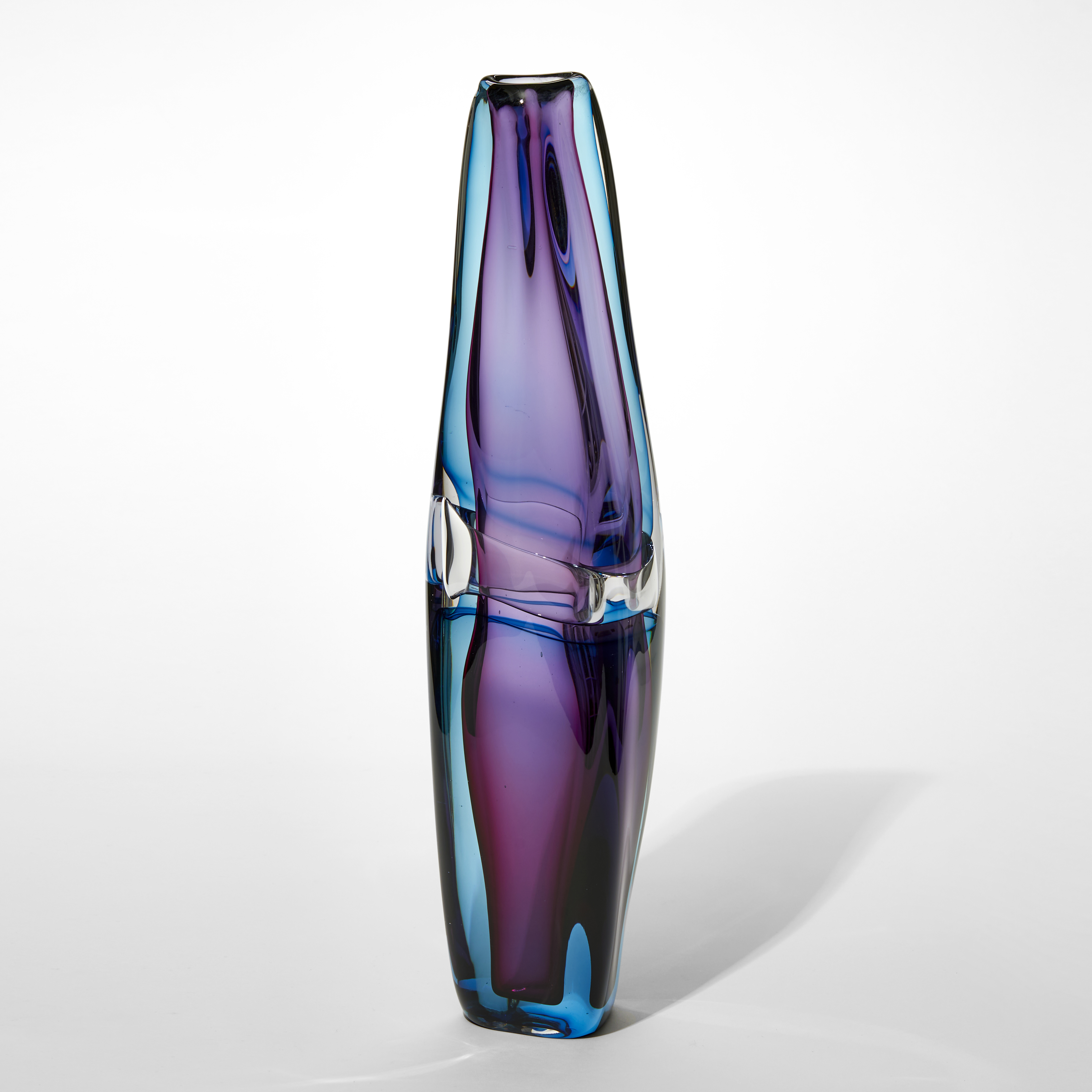 lava lamp like vase in transparent aquamarine with an inner layer of purple with fluid lines and undulations and a central clear band at the waist hand made from glass