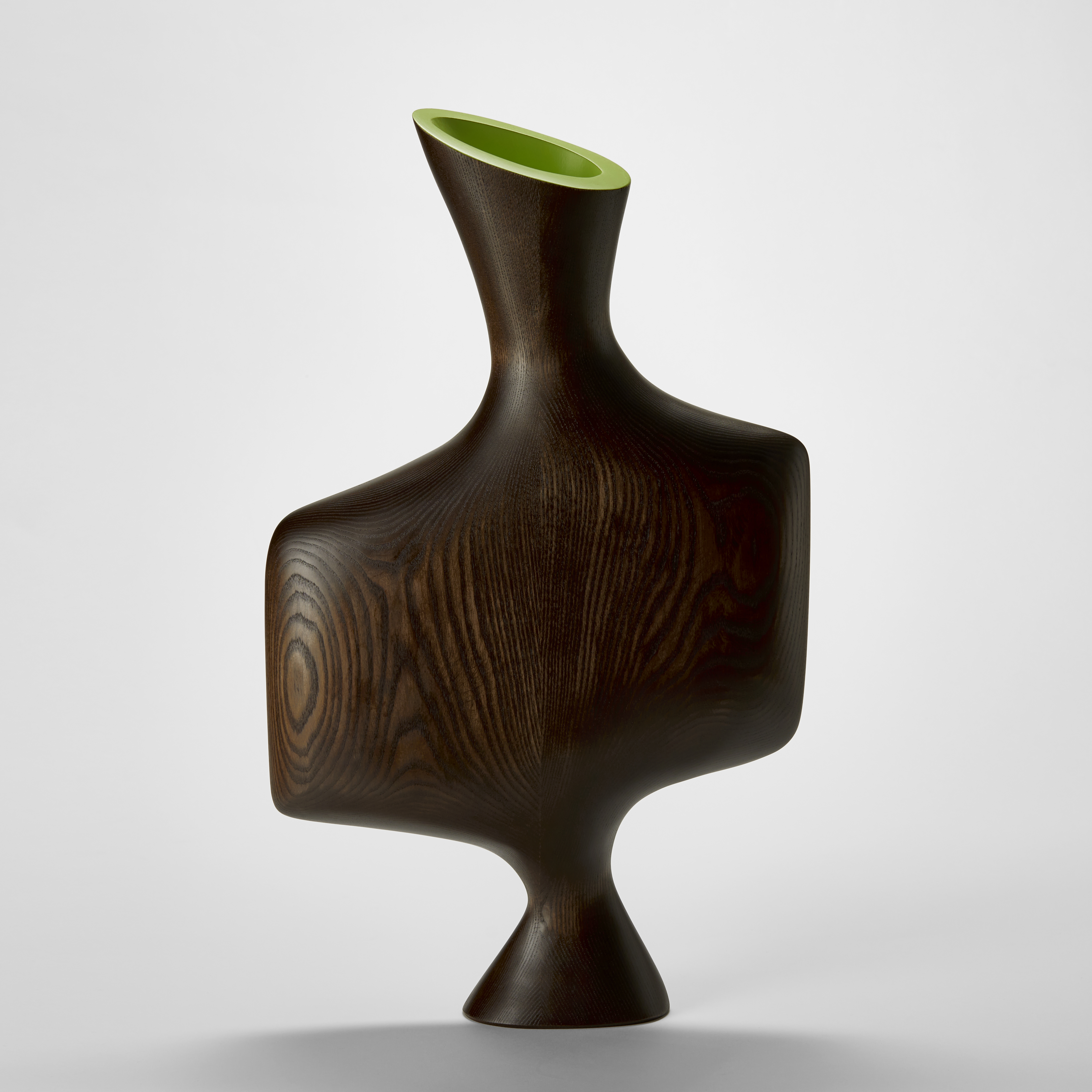tall wooden sculpture with smooth surface and rounded edges and a flared cone base and widened square central torso section with broad shoulders leading to a angled cone opening with a bright lime green interior