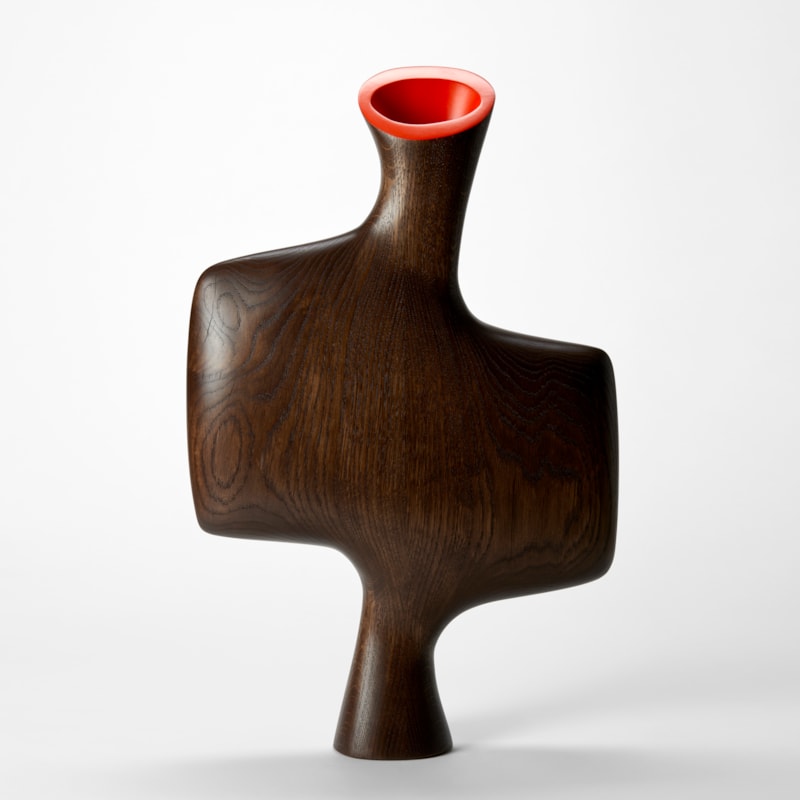 abstract standing sculptural vessel hand made from oak with asymmetric form  in the shape of a bisected offset square with flat front and back a tapered foot and top angled opening in bright red