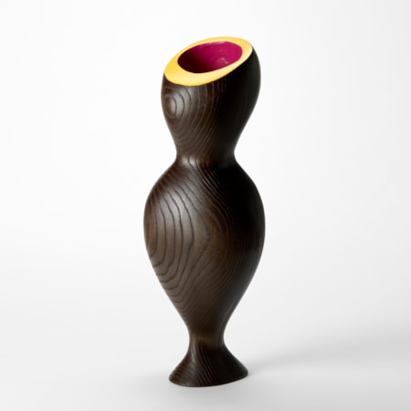 undulating hour glass shaped wooden sculpture with ridged contour lined surface and top opening with a flat angled rim in bright yellow and inner cavity in bright pink