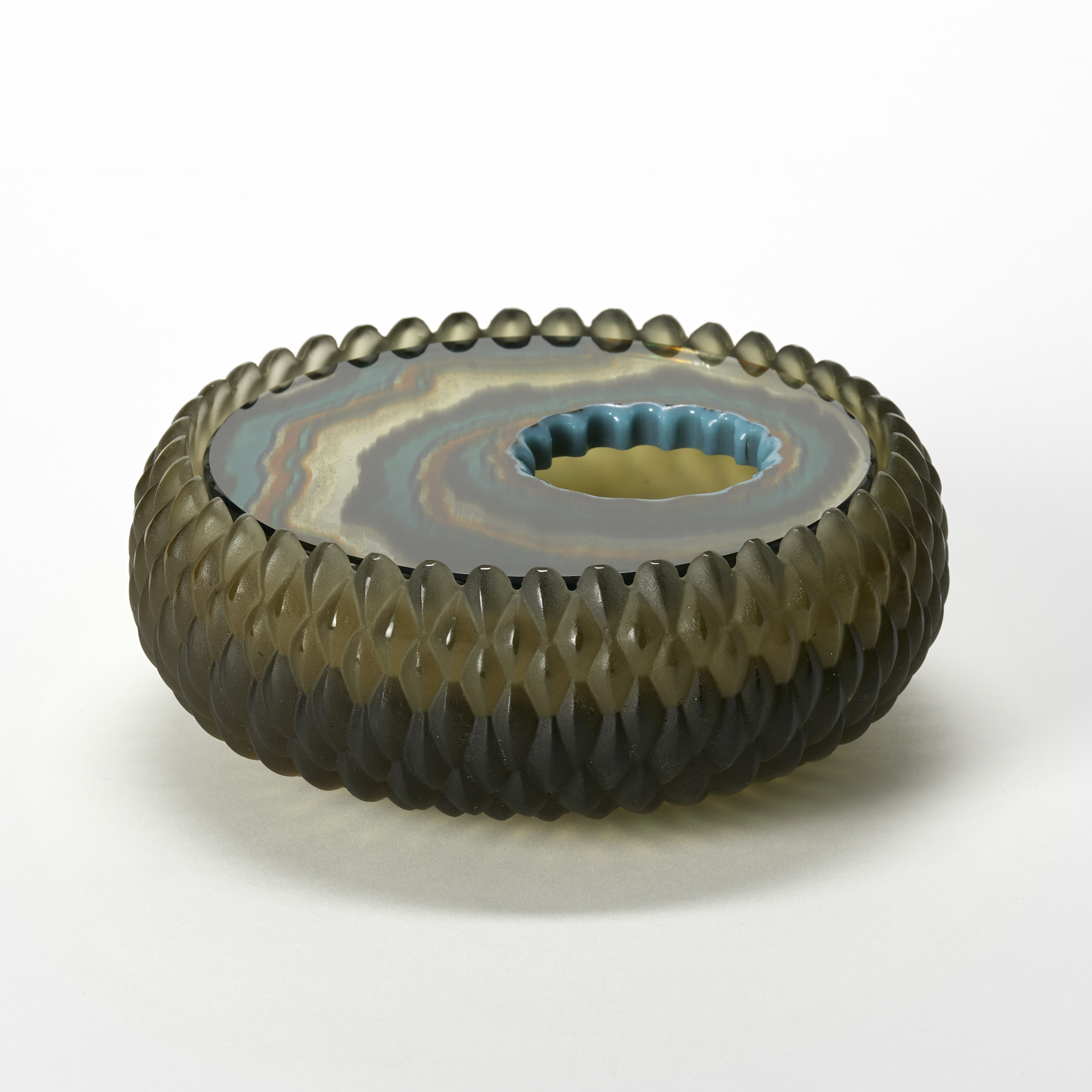 round low box with curved sides and an opaque matt exterior surface with a relief repeat diamond pattern in bronze olive green and an inset polished lid with organic bands of colour in rust black jade green and brown hand made from glass