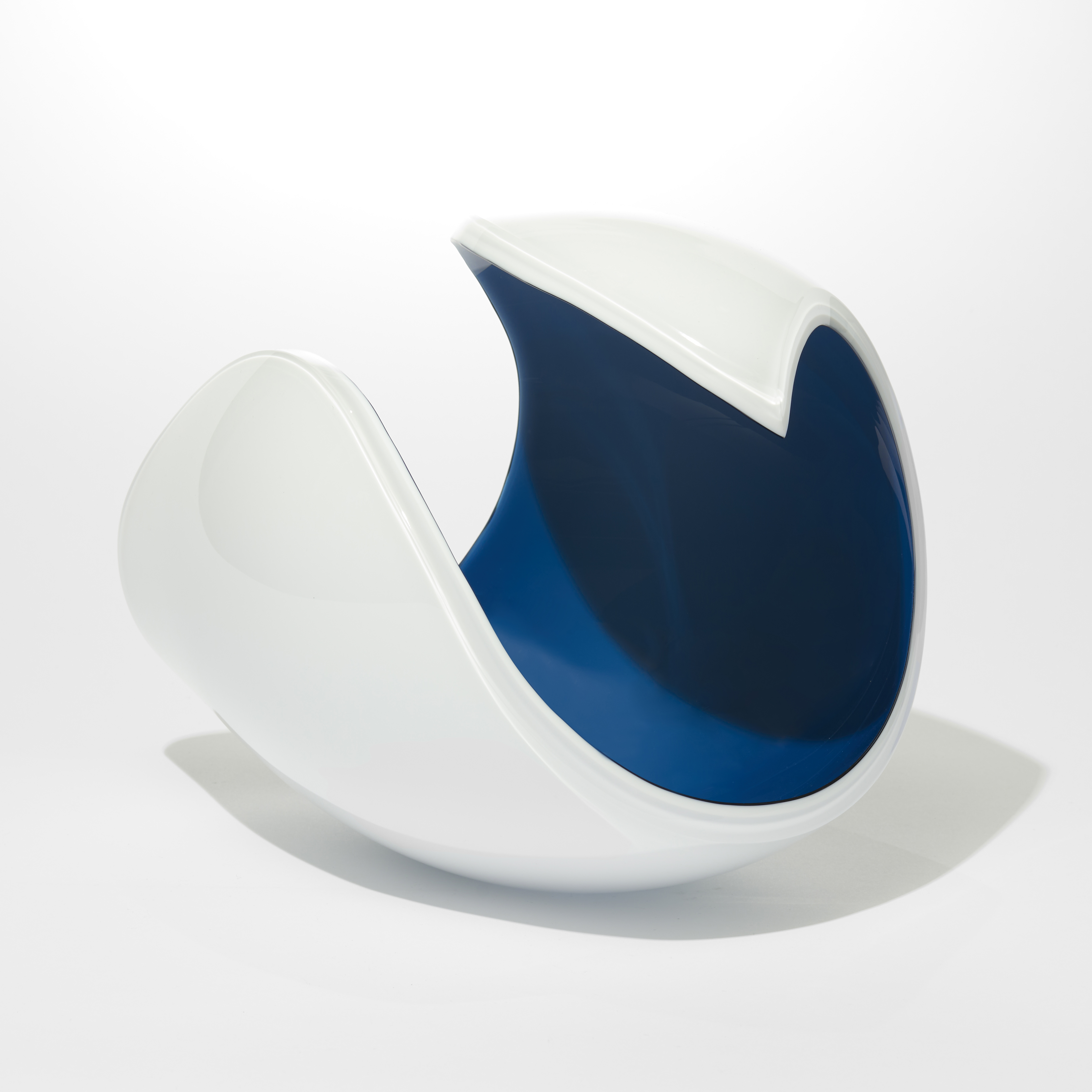 rounded form with opaque white exterior and dark midnight blue interior with a curved rim curling to a final point like the golden section hand made from glass