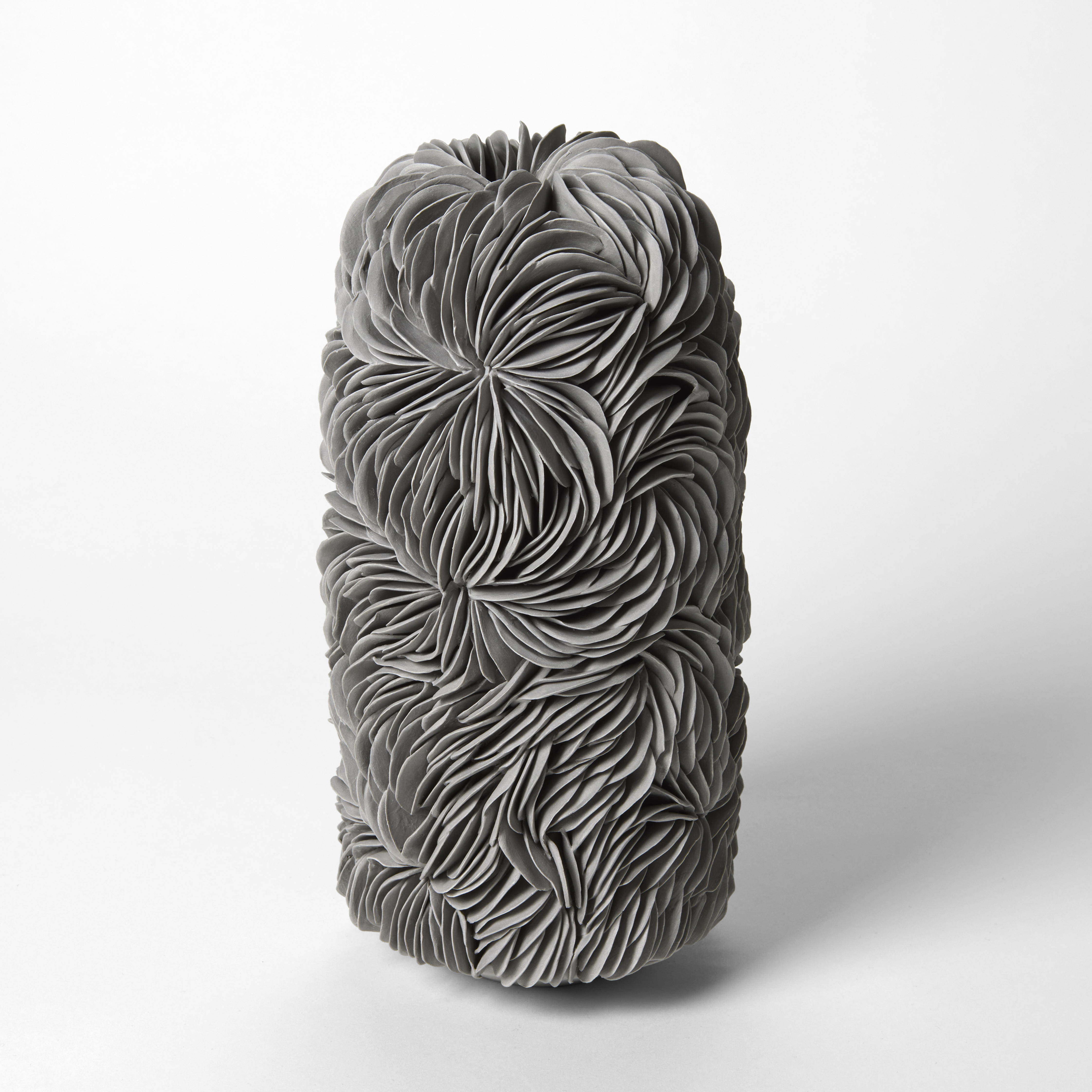 tall lozenge standing grey vessel with a tiny opening on the domed top covered in curved interlocking shards hand made from thrown and sculpted stained porcelain  