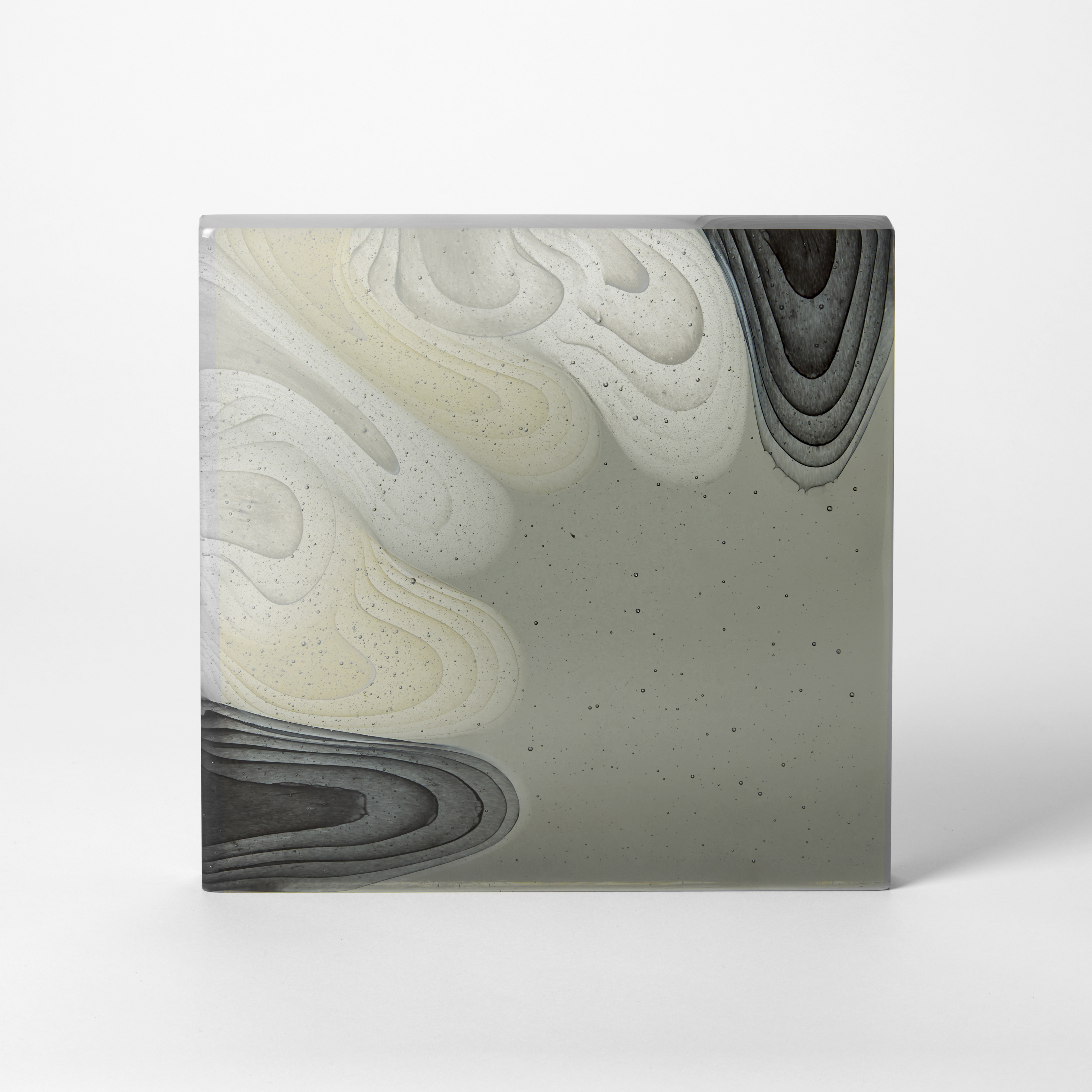 square opaque standing grey slab with concentric droplets in white cream and black emerging from the top and left sides spreading across the form hand made from cast glass