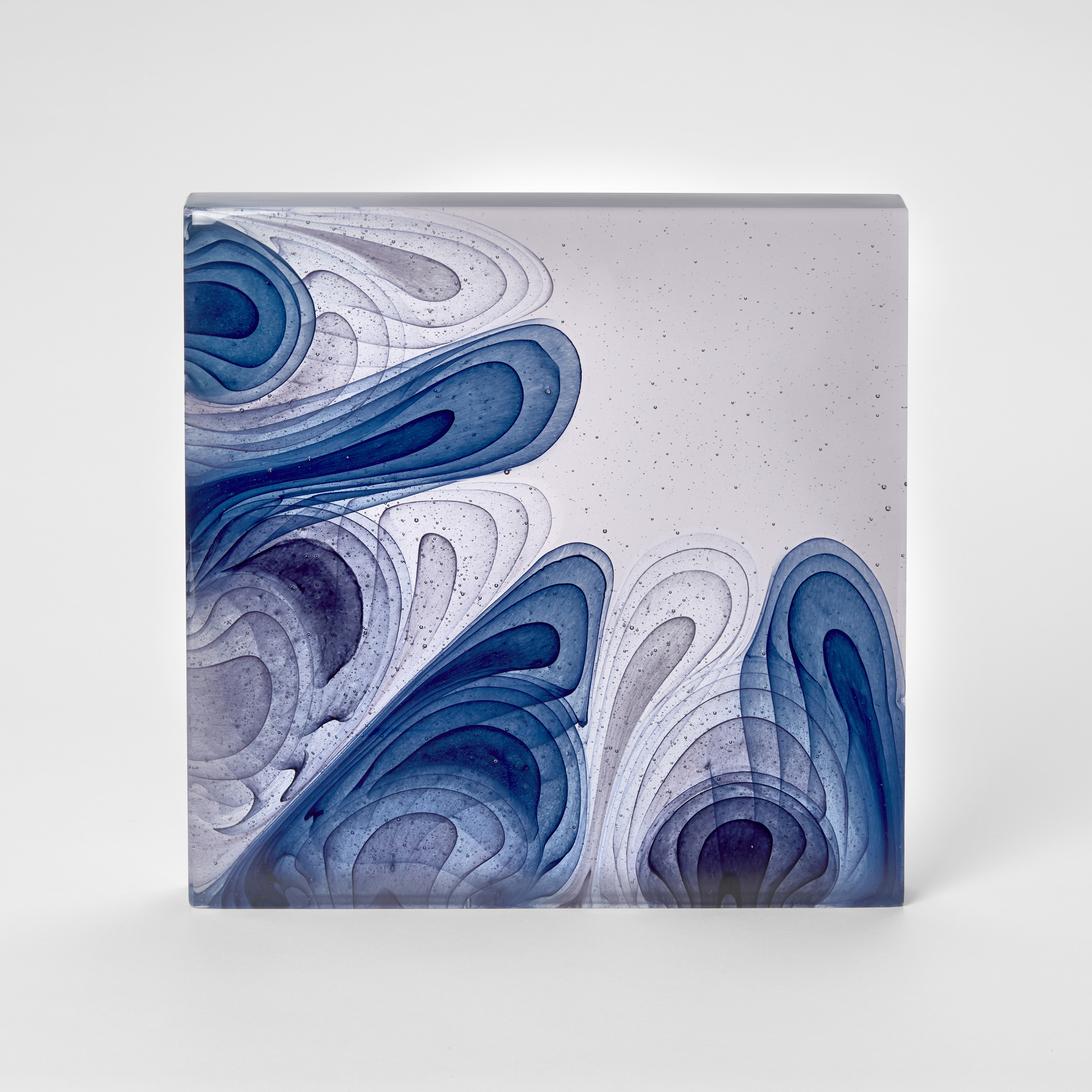 square standing pale lavender slab with concentric droplets in blue and grey rising from the base and left hand side across the form hand made from cast glass