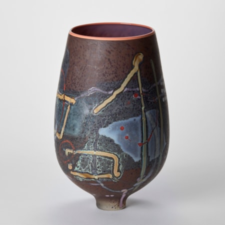 tulip flower shaped vase with a rich aubergine  glossy interior salmon pink rim and a matt exterior covered in abstract patterns and lines in blue lilac chocolate red and olive hand made from glass perched on an elegant tapering foot