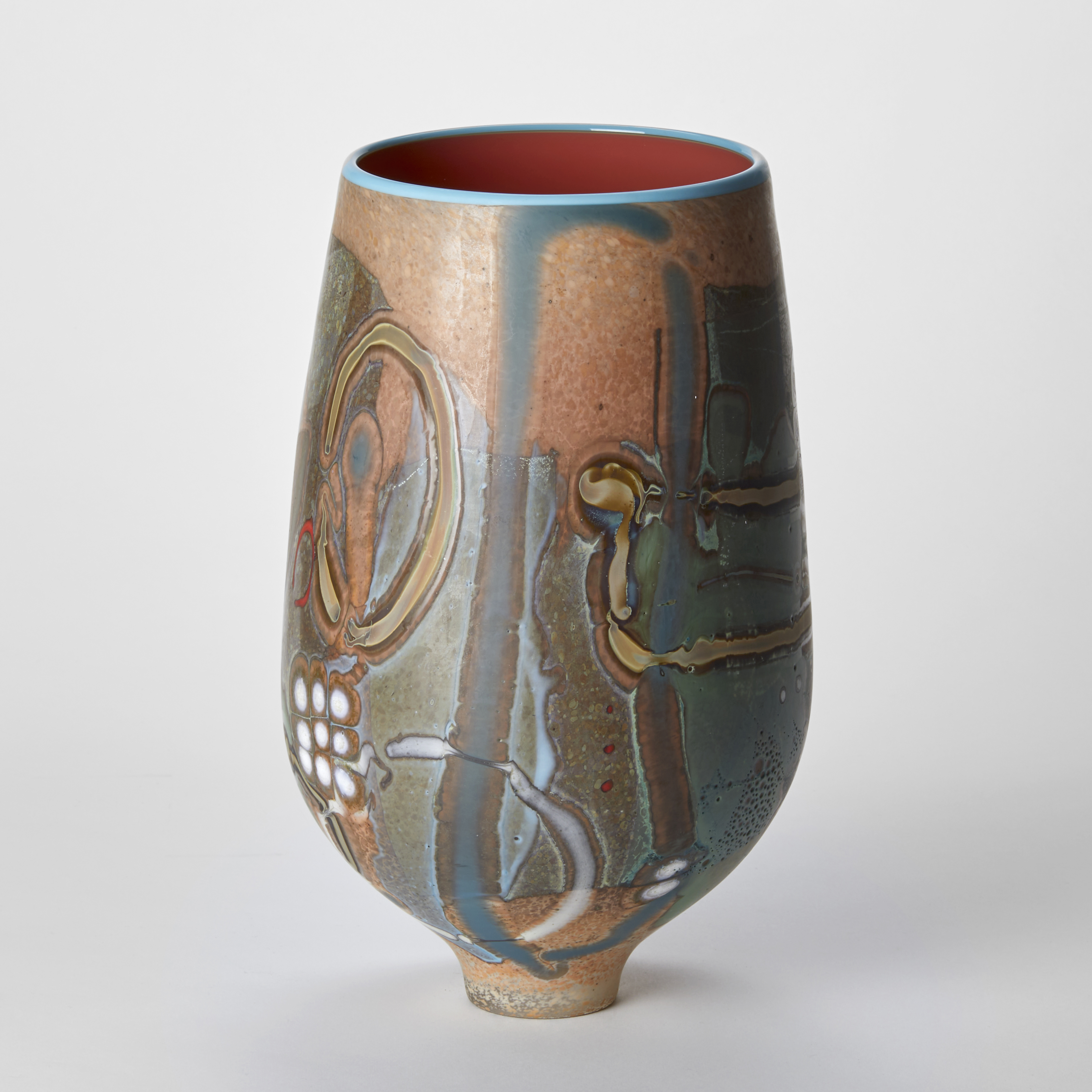 bulb shaped vase with wide opening and glossy salmon interior with a blue rim with a matt exterior covered in abstract lines and patterns in light brown jade green white and red hand made from glass with a narrow elegant foot