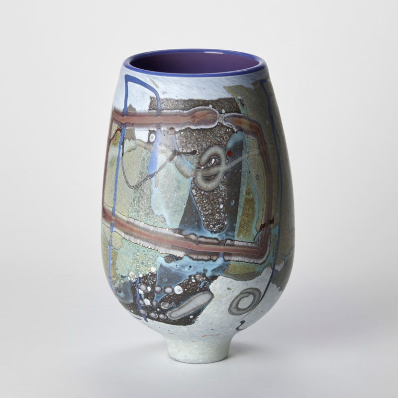 tulip shaped vessel with tapering narrow elegant foot with a matt exterior covered in abstract flat linear patterns and lines in white olive midnight blue and ochre with a glossy purple interior hand made from glass