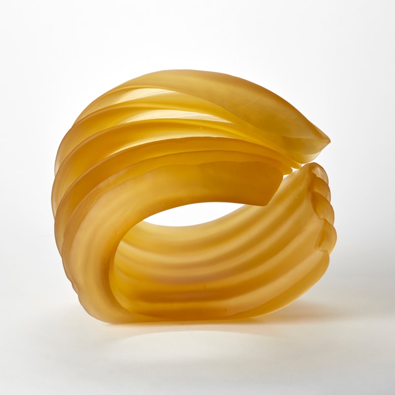 opaque golden yellow ridged sculpture with the appearance of a curl of butter hand made from cast glass