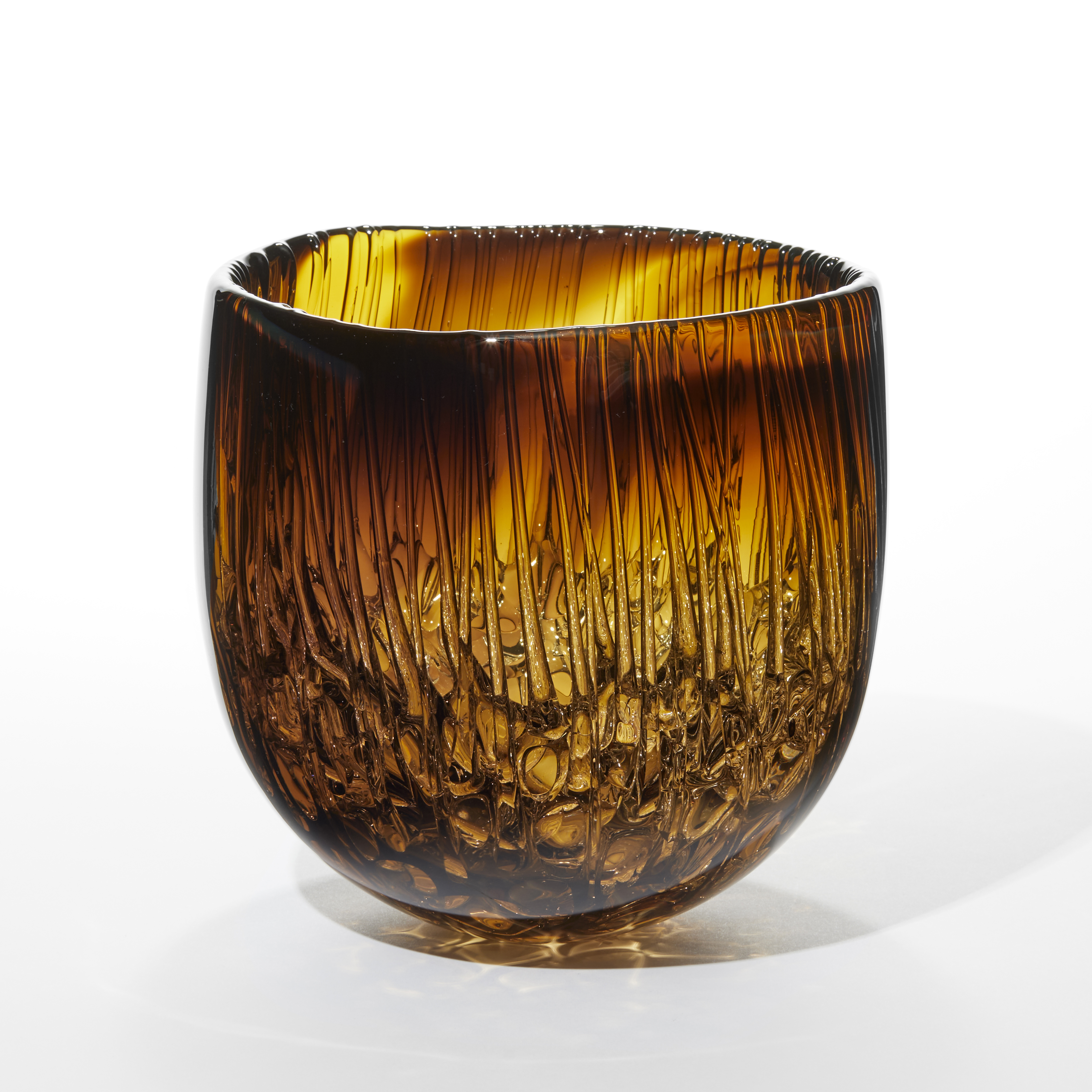 transparent merging brown and amber bowl with a rounded bottom glossy exterior and interior with drips running down the sides pooling in the bottom hand made from glass