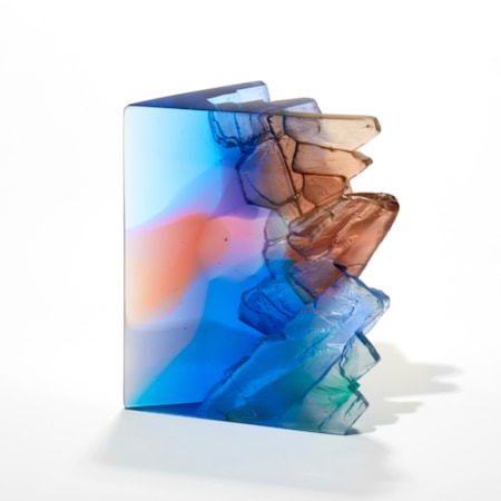 cliff and landscape inspired artwork in transparent blues pink peaches jade and aubergine with two vertical glossy sides and top and one side with a craggy cliff edge like texture hand made from cast glass