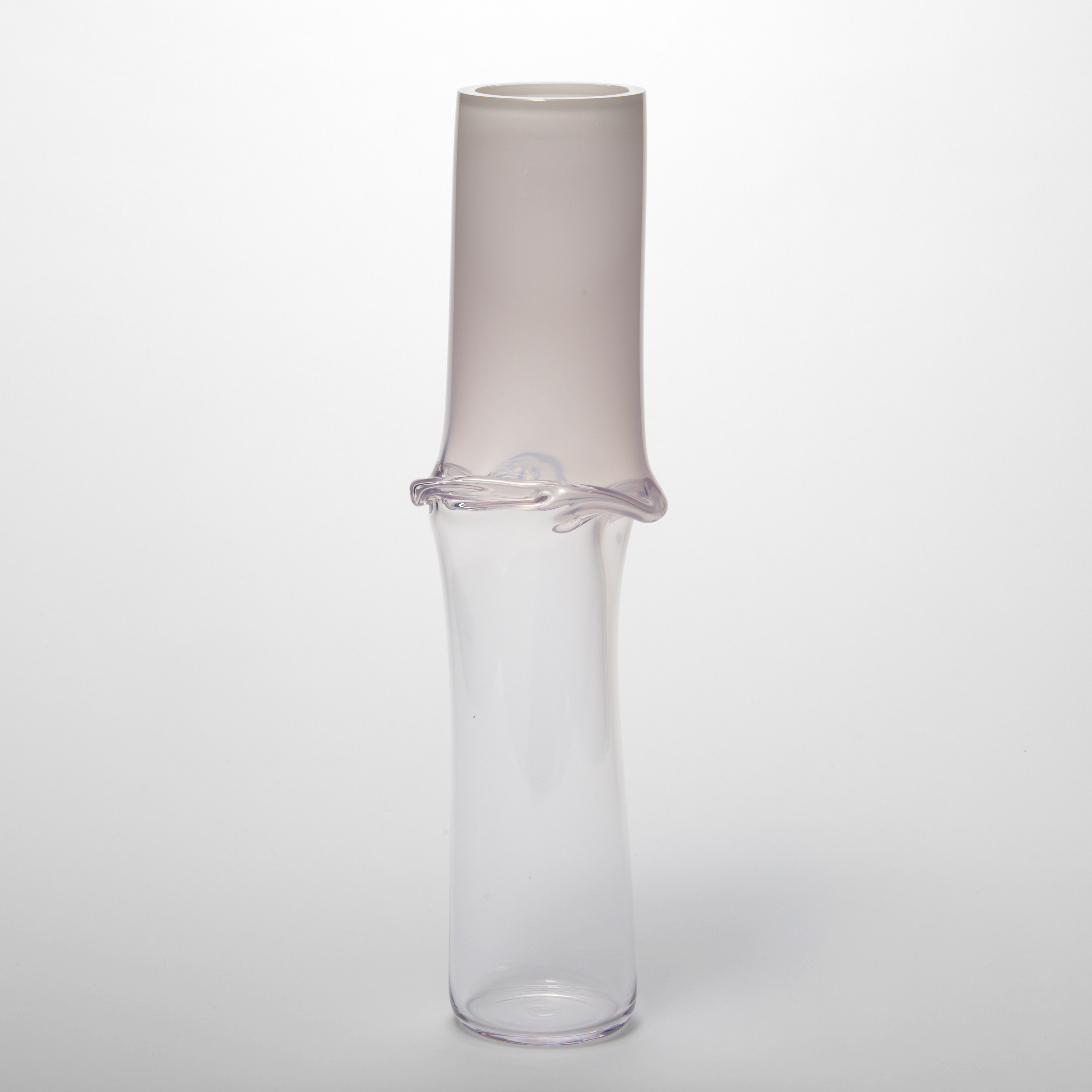 tall slightly undulating tubular vessel with a soft off white top half fading to clear with a creased centred horizon line hand made from glass