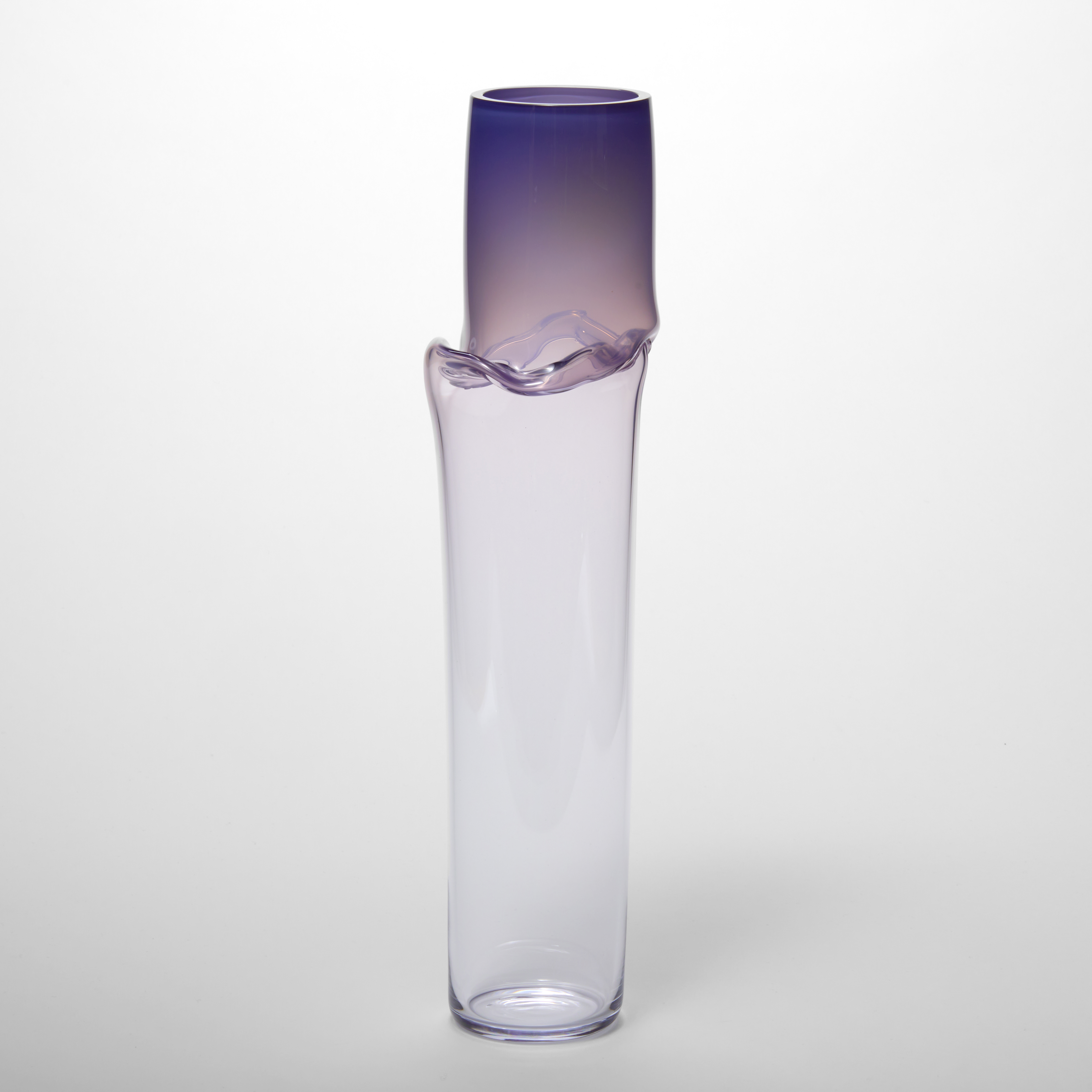 tall tubular vessel in soft purple plum fading to a clear with a creased raised wavy line a quarter of the height from the top hand made from glass