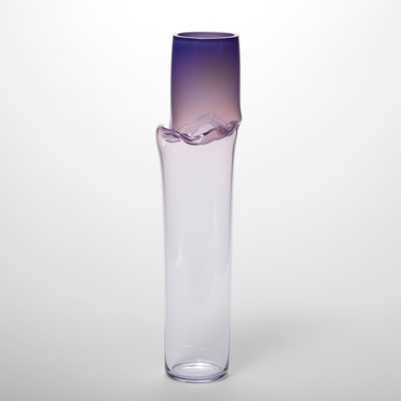 tall tubular vessel in soft purple plum fading to a clear with a creased raised wavy line a quarter of the height from the top hand made from glass