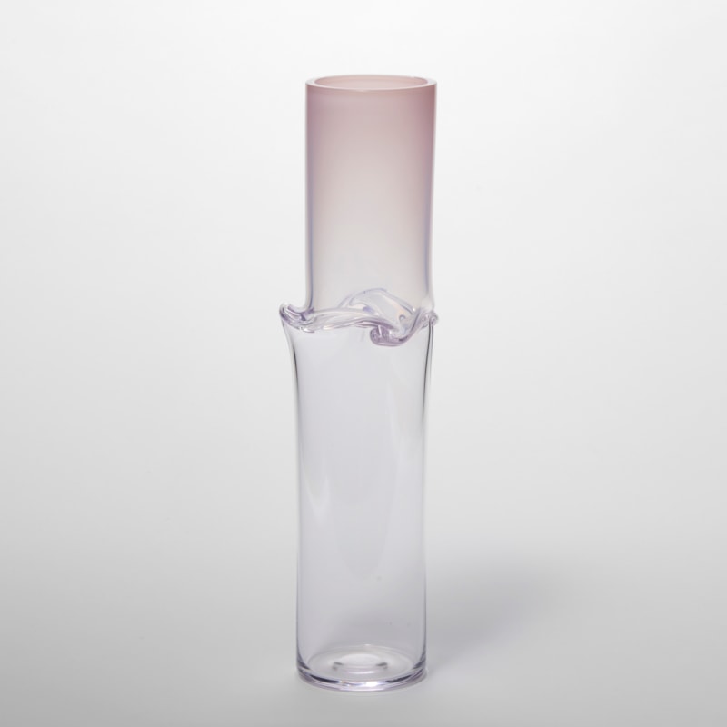 tall soft pink fading to clear cylindrical vessel with a flared and three dimensional raised creased waist hand made from glass