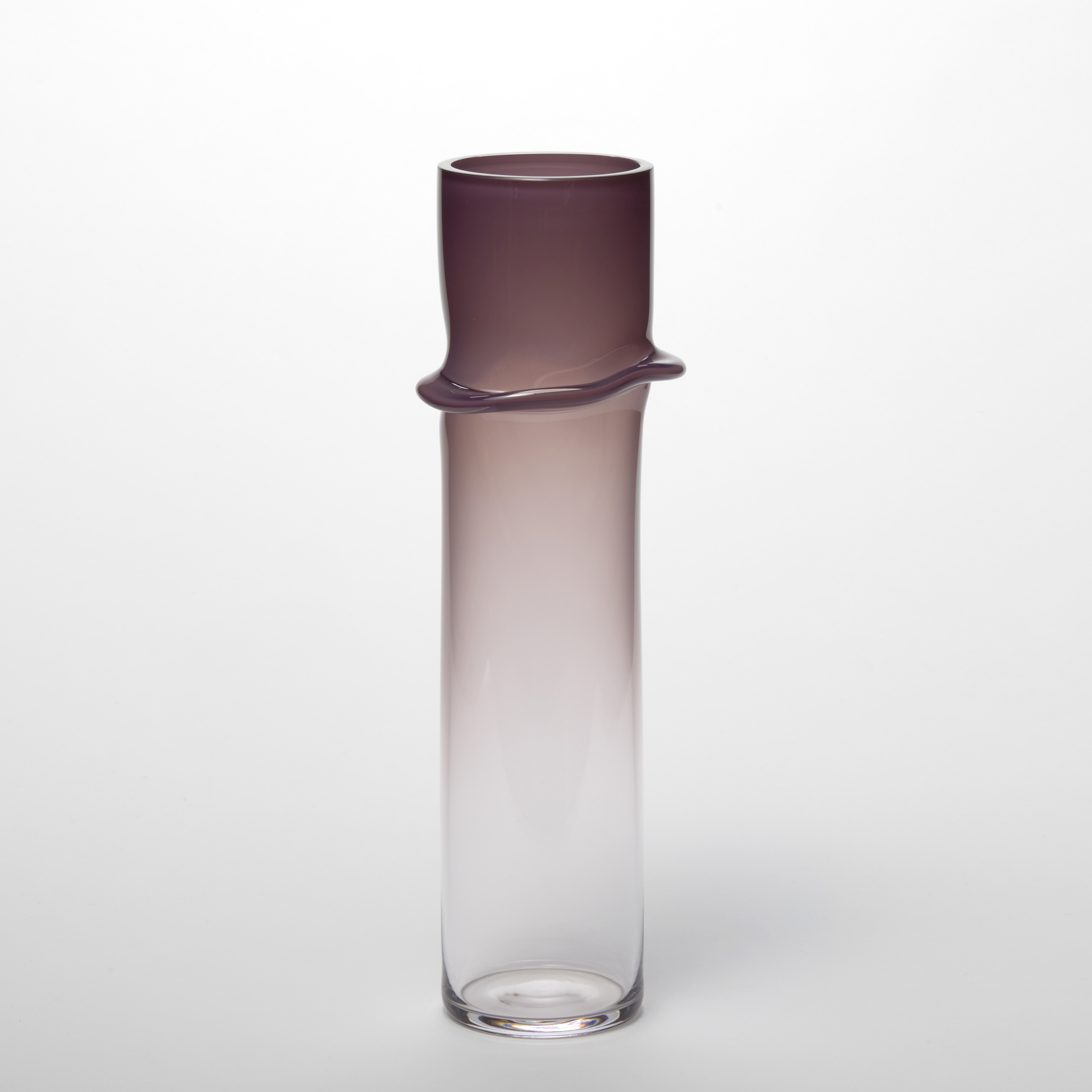 cylindrical vessel with soft opaque plum top fading to a transparent bottom half with a pronounced wavy creased raised line a quarter from the top hand made from glass