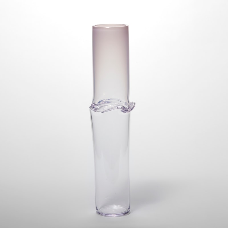 tall cylindrical vessel with soft pink top half fading to a clear bottom half with a creased and folding band around the waist hand made from glass