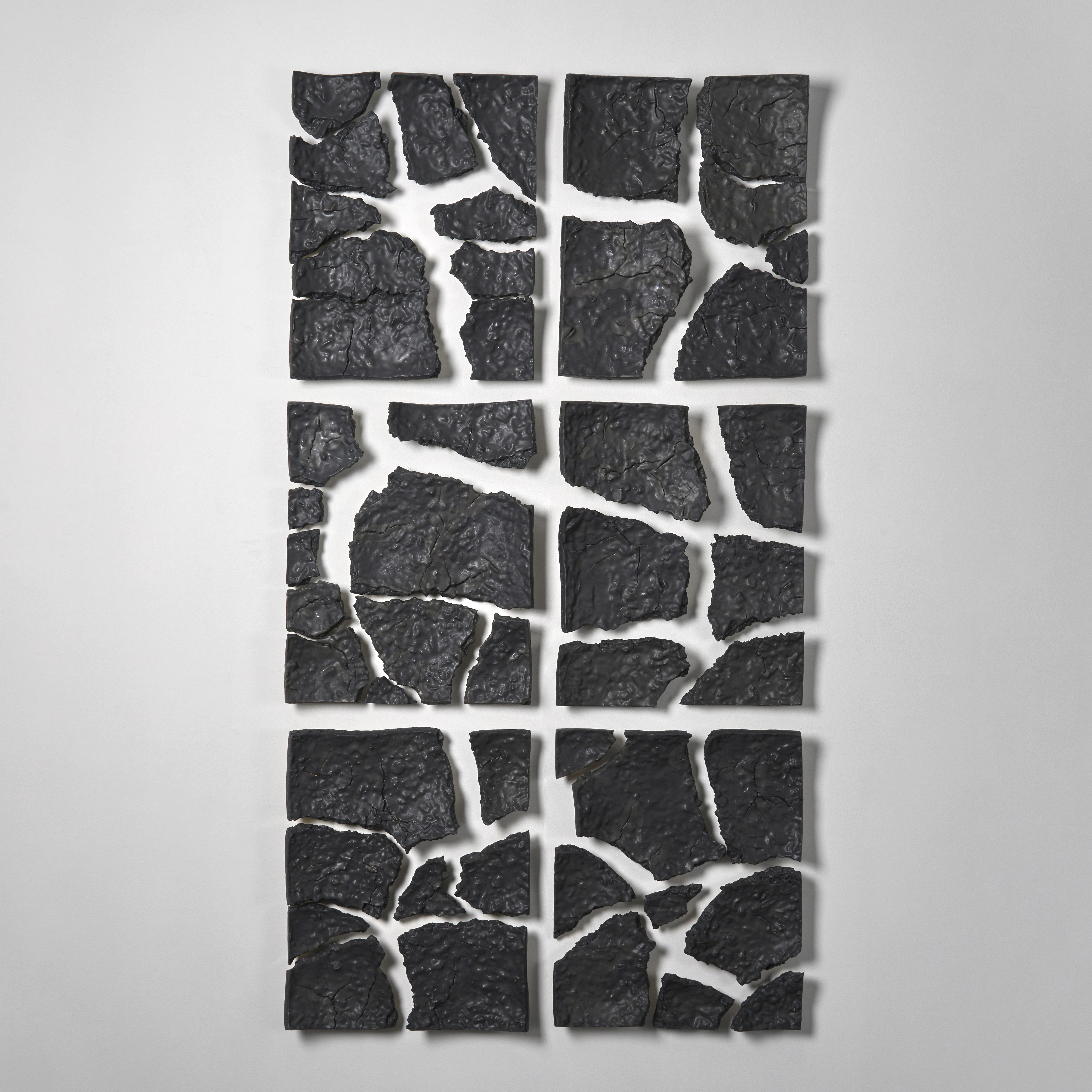 black and softly textured wall mounted portrait configured set of 6 fractured rectangular set of shards with the appearance that each has been broken and pulled apart yet retaining the outer perimeter for each hand made from clay