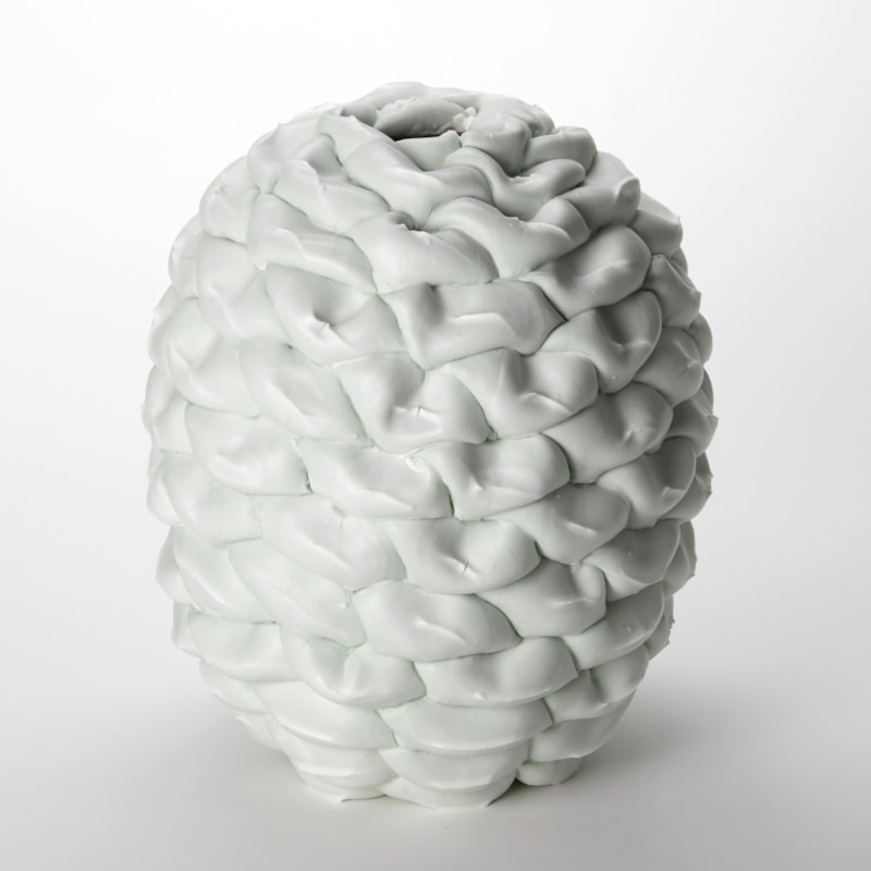 light celadon coloured pinecone inspired vessel created from stacked soft rings each with a pinched white seamed edge hand made and thrown from porcelain stoneware and parian