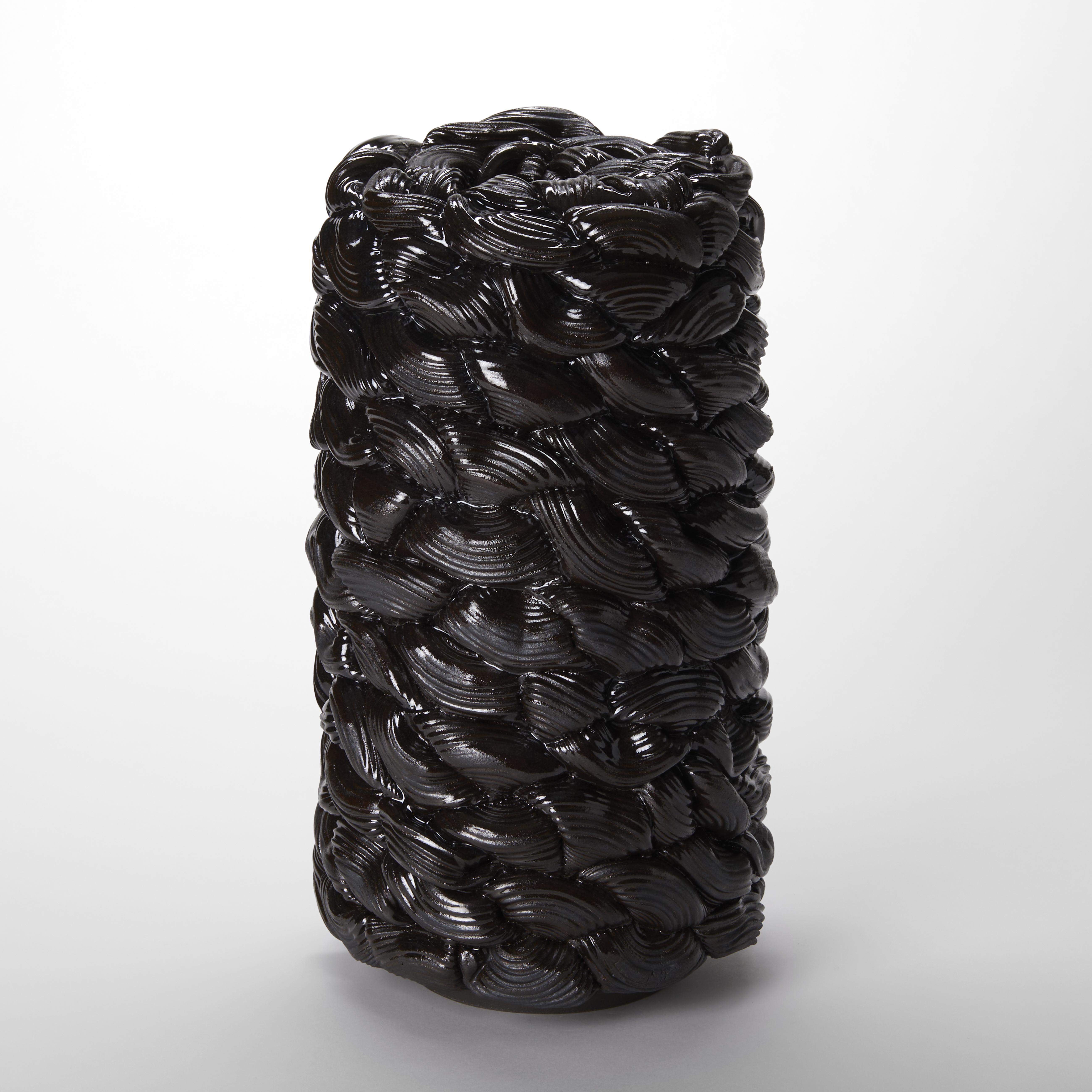 blackish brown glistening column created from interwoven ridged rings twisting into one another and stacked on top of each other hand made from stoneware clay