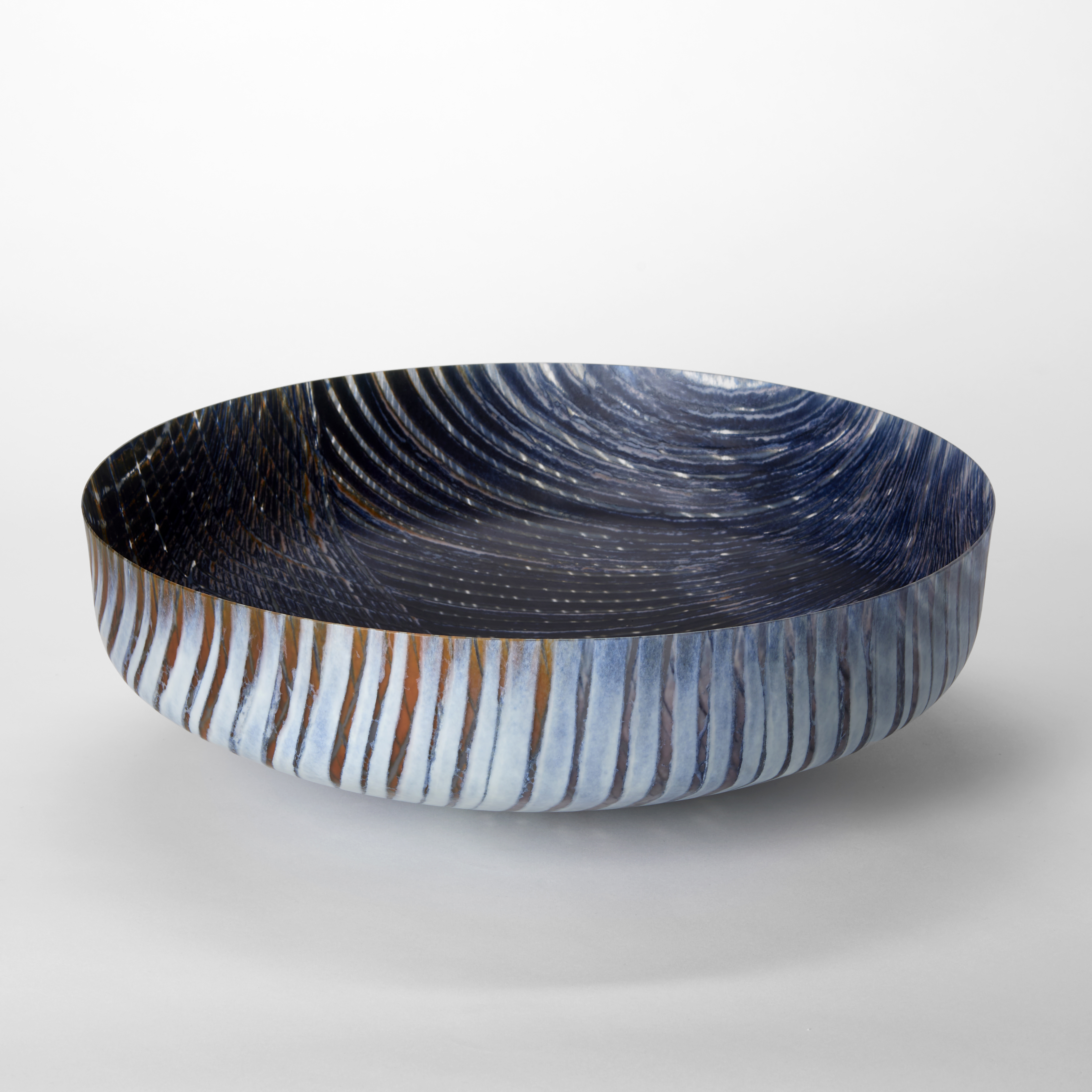 round opaque bowl in dark blue light grey and rust with organic curved lined patterns on the inside and outside hand made from fused glass