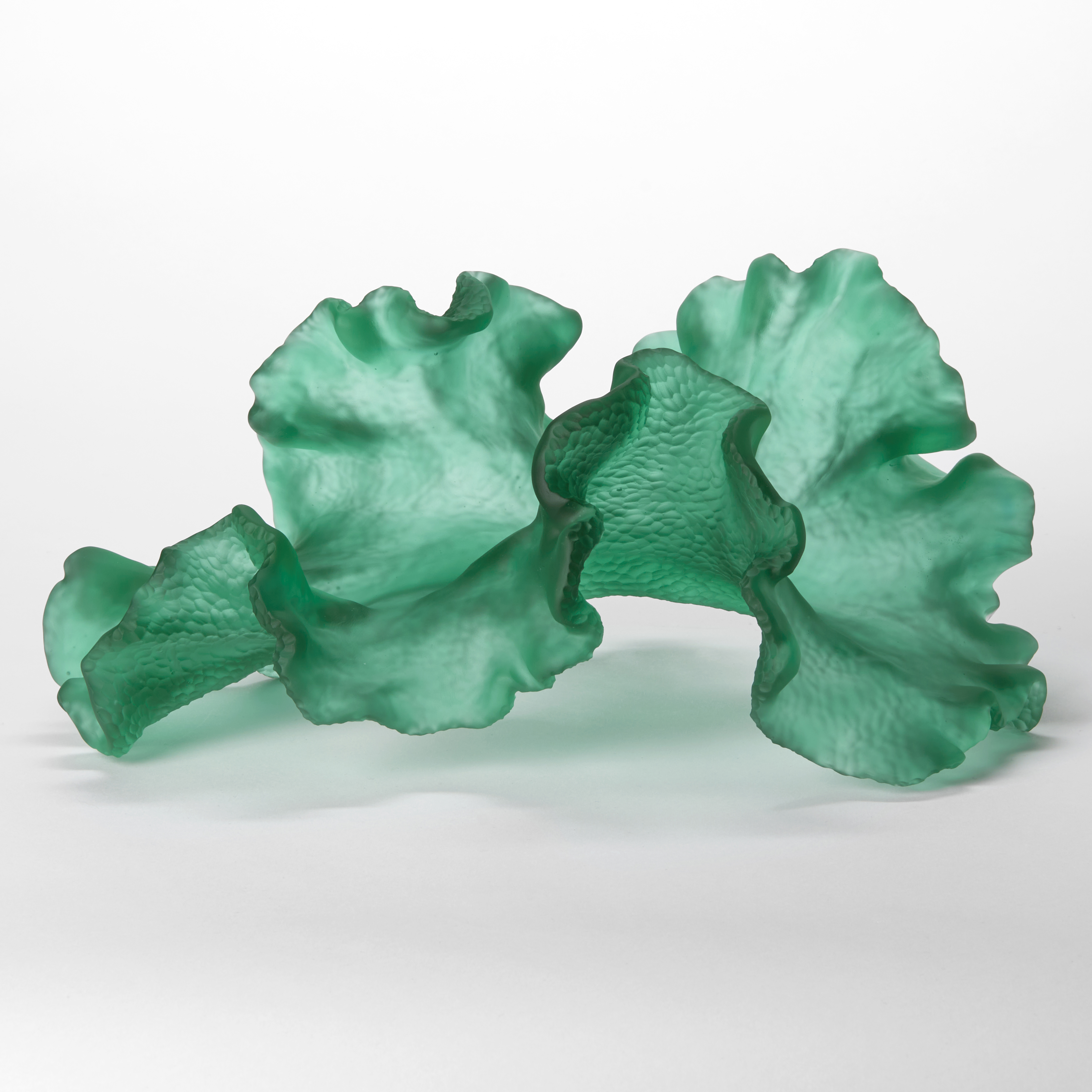 opaque dappled soft emerald green organic sculpture with the appearance of a floating piece of seaweed with frilled undulating edges and a finely scolloped textured underside hand made from glass