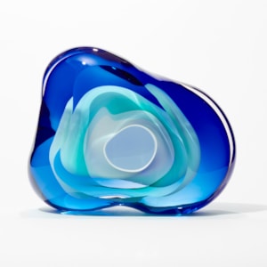 soft transparent amorphous organic rock inspired sculpture with front aperture opening in layers of clear intense blue and turquoise with a central cavity lined in opaque white hand made from glass
