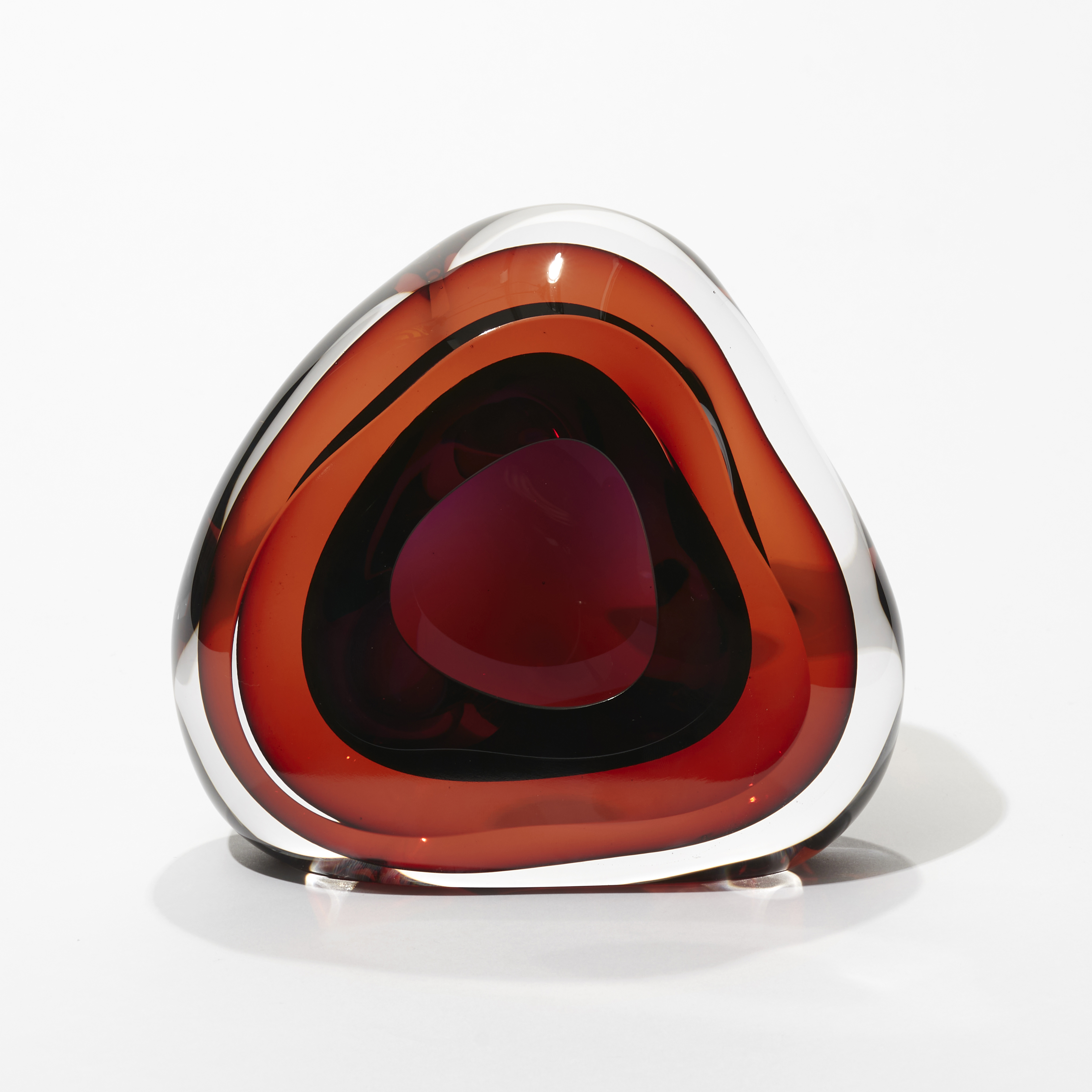 soft triangular transparent organic geode inspired sculpture with layers of colour in orange and purple with an internal cavity and front opening hand made from glass