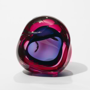 transparent pink and indigo blue geode inspired sculpture with a soft undulated amorphous shape and central cavity and front facing opening hand made from glass