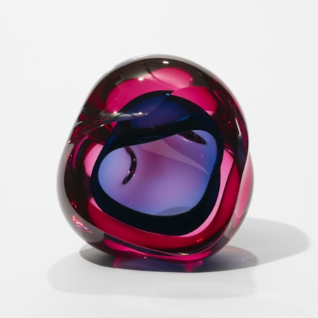 transparent pink and indigo blue geode inspired sculpture with a soft undulated amorphous shape and central cavity and front facing opening hand made from glass