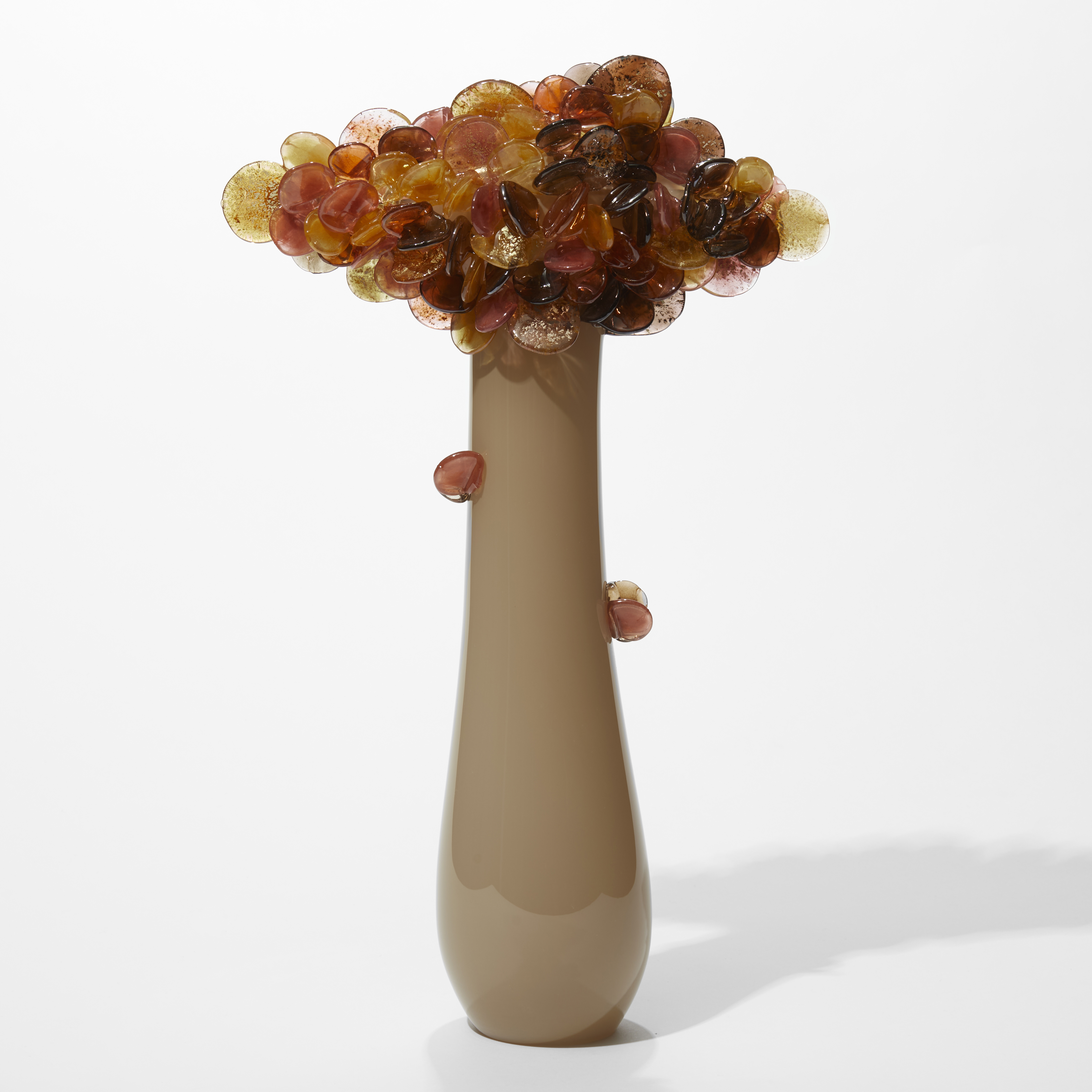 tall tree inspired sculpture with opaque long taupe sleek pear shaped trunk with a diamond shaped cluster of rounded leaves at the top in aubergine pink orange and amber with gold leaf flecks hand made from glass