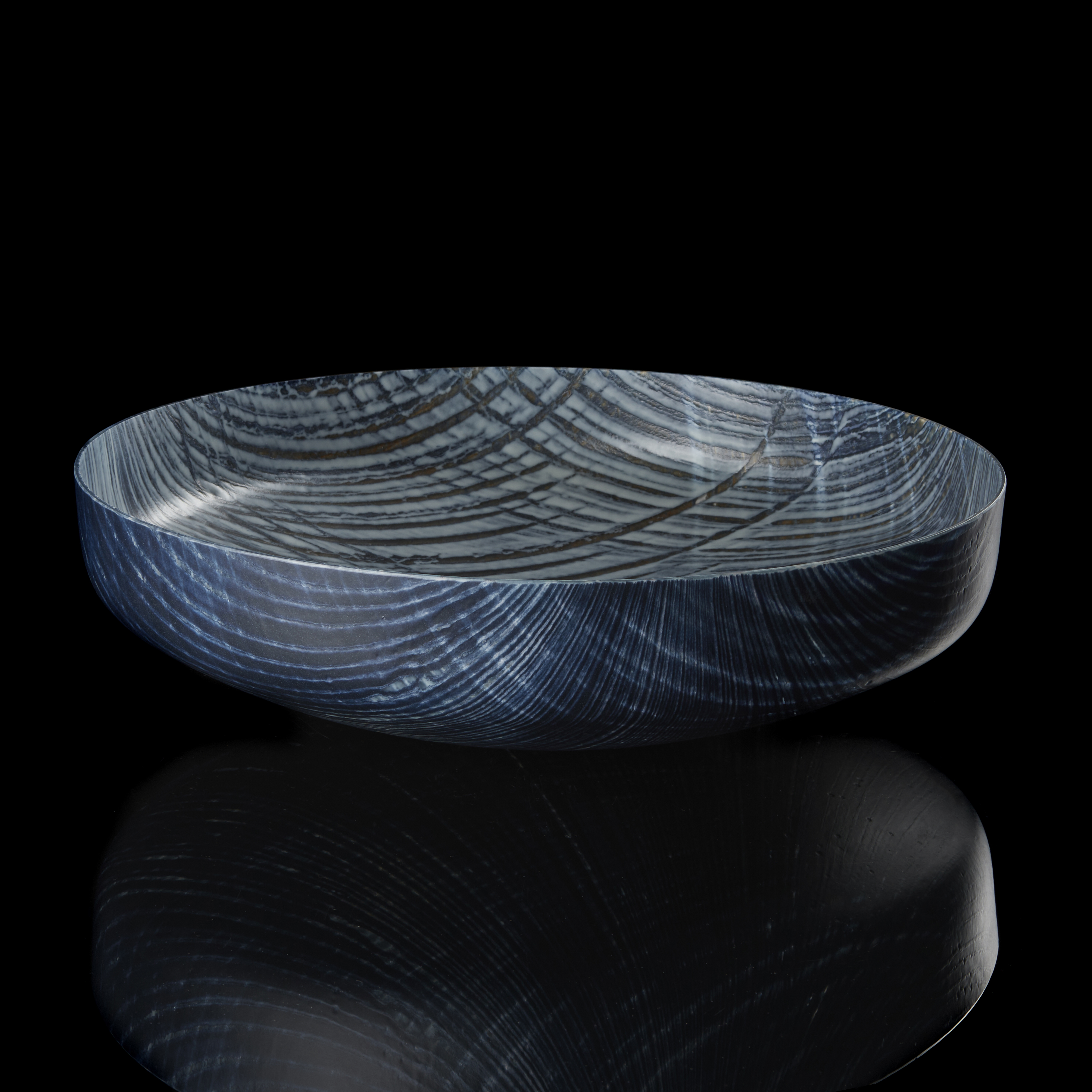 round centrepiece with curved base in soft dove grey and indigo blue with lined curved organic patterns over the surface hand made from glass