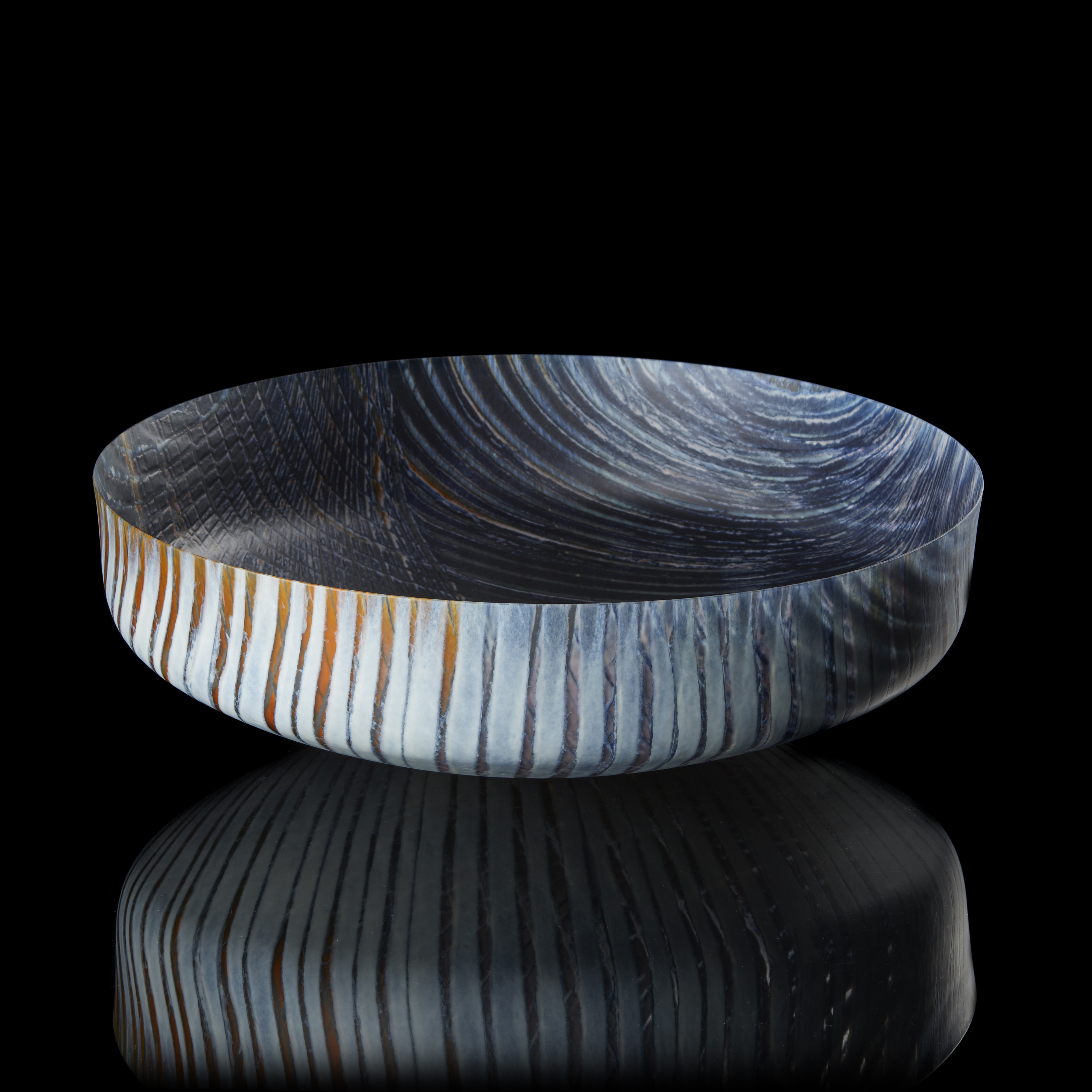 round opaque bowl in dark blue light grey and rust with organic curved lined patterns on the inside and outside hand made from fused glass