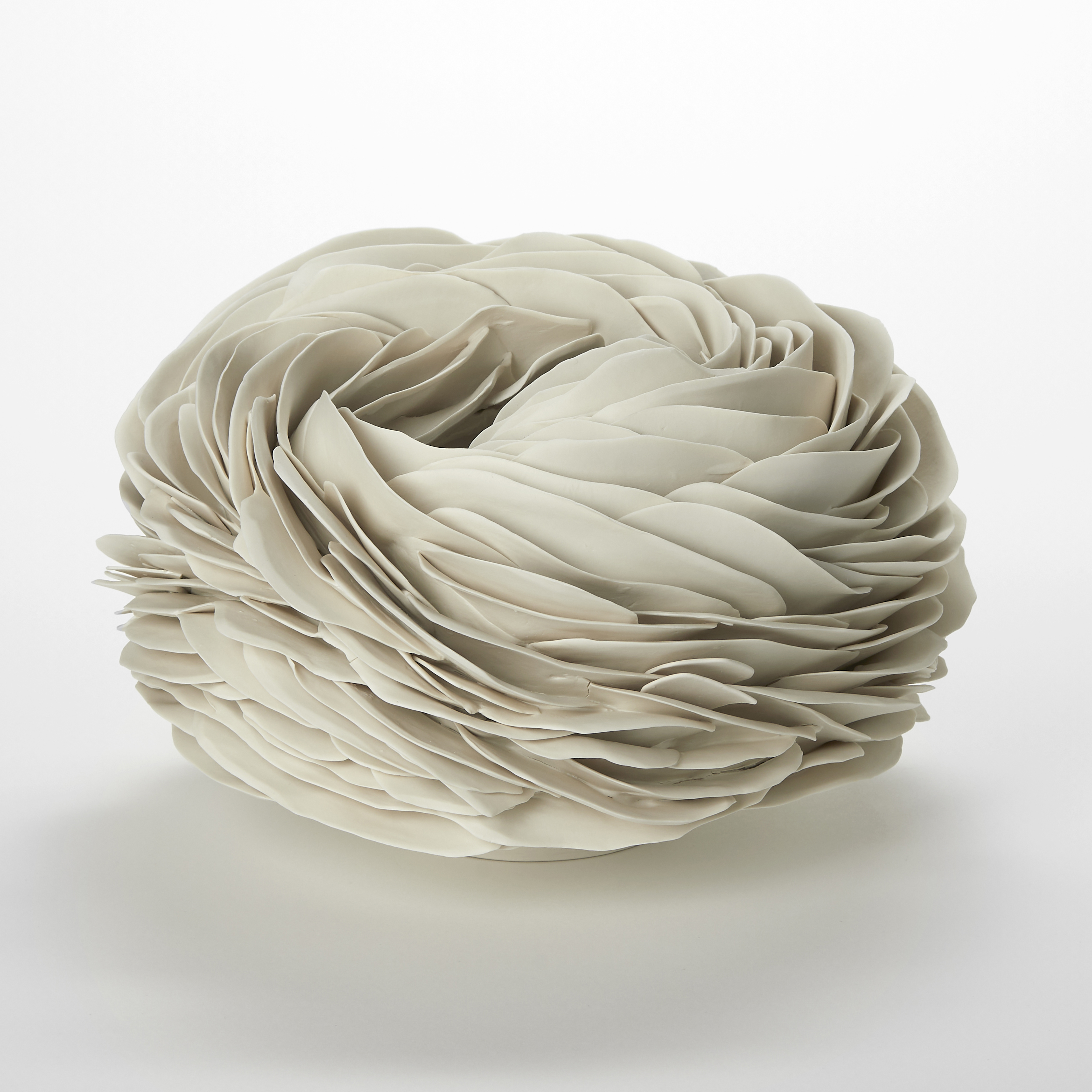 cream alabaster low round organic vessel with a small top opening with the surface covered in tightly interwoven and stacked long thin undulating fins and shards hand made from porcelain