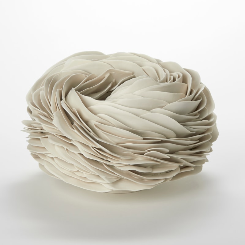 cream alabaster low round organic vessel with a small top opening with the surface covered in tightly interwoven and stacked long thin undulating fins and shards hand made from porcelain