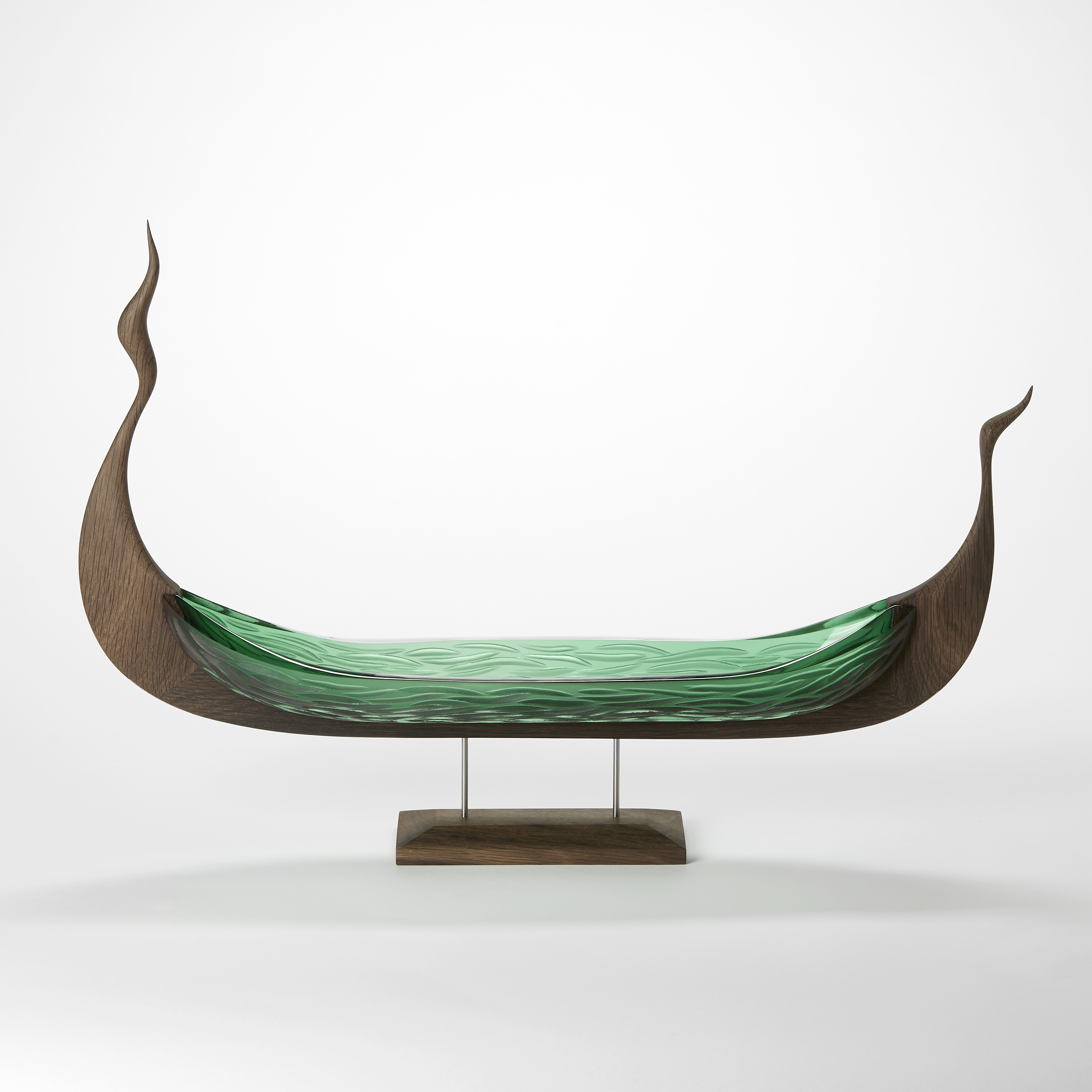 stylised viking ship with undulating oak framework and keep with a green glass hull with a wavy cut pattern standing aloft on an elegant stand
