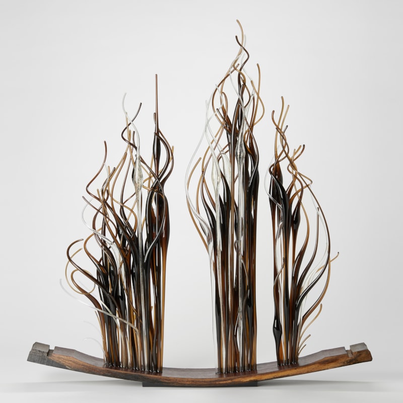 curved slice of oak from a barrel with three bunched sections of straight thin canes with curling ends in amber brown and clear protruding from the top edge and thrusting upwards with each hand made from glass