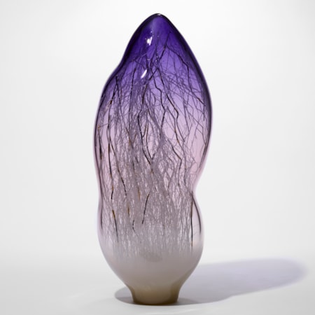 tall amorphic sculpture in transparent purple fading at the bottom and turning to milky opaque white with fine long canes in white black and gold trapped on the inside hand made from glass