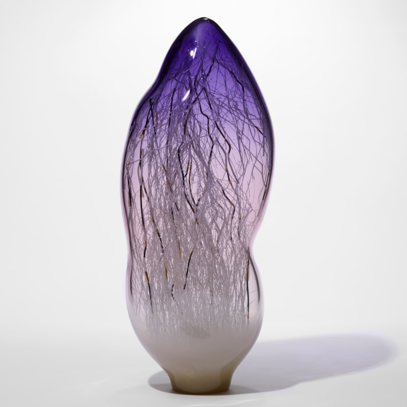 tall amorphic sculpture in transparent purple fading at the bottom and turning to milky opaque white with fine long canes in white black and gold trapped on the inside hand made from glass
