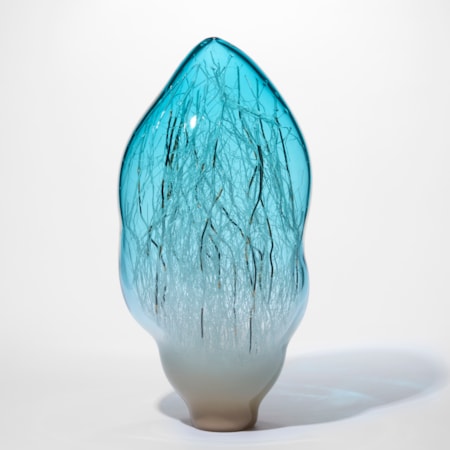 standing amorphic sculpture in transparent aquamarine fading towards the base turning to milky warm white with the internal filled with fine canes in white black and gold made from hand blown glass
