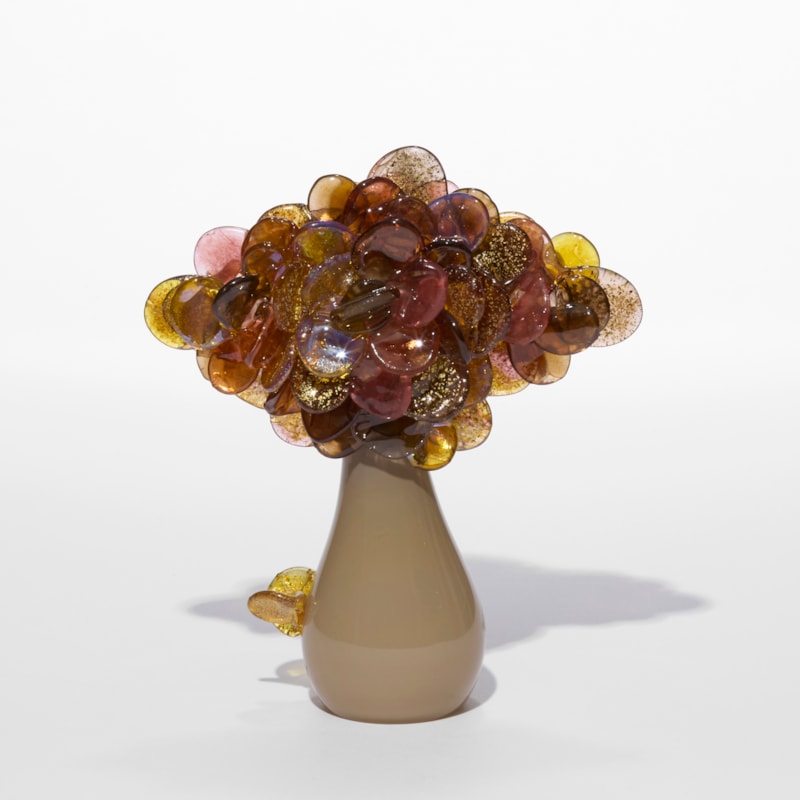 cute dinky simplified tree sculpture with a glossy pear shaped fawn coloured trunk and a diamond shaped cluster of rounded lollipop leaves in aubergine amber and pink with gold encased flecks hand made from blown glass