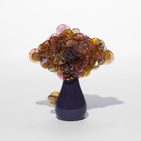 small cute simplified tree sculpture with a pear shaped glossy trunk in plum and a cluster of shiny lollipop round leaves clustered on the top in aubergine pink and amber with gold flecks trapped within each leaf hand made from blown glass