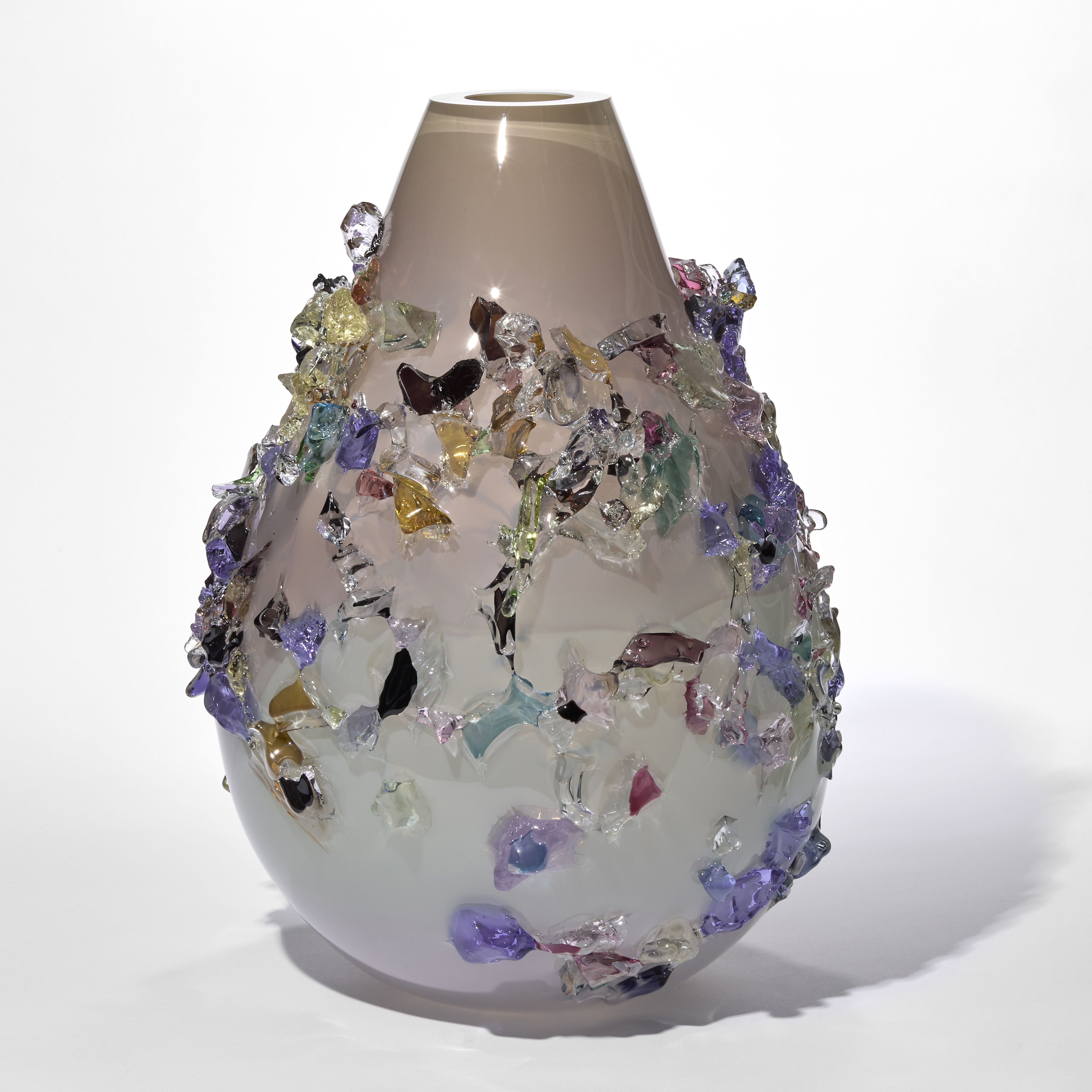 large teardrop shaped vase in milky white fading to a soft peach neck covered in glistening shards in purple blue pink jade amber and dark brown hand made from glass