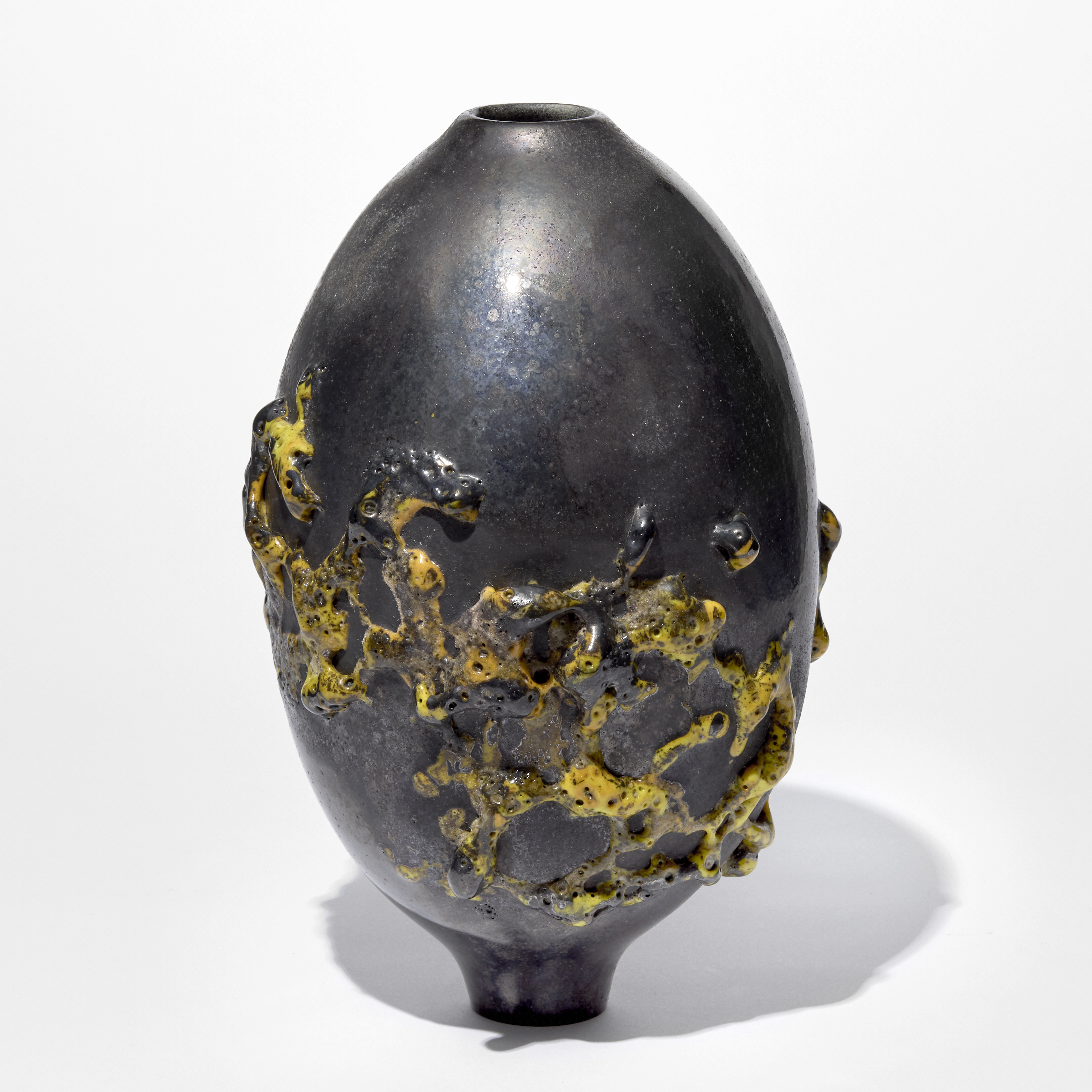 rounded pewter coloured pill shaped sculptural vessel with an organic swathe of raised bright yellow organic trails navigating the lower half hand blown from glass