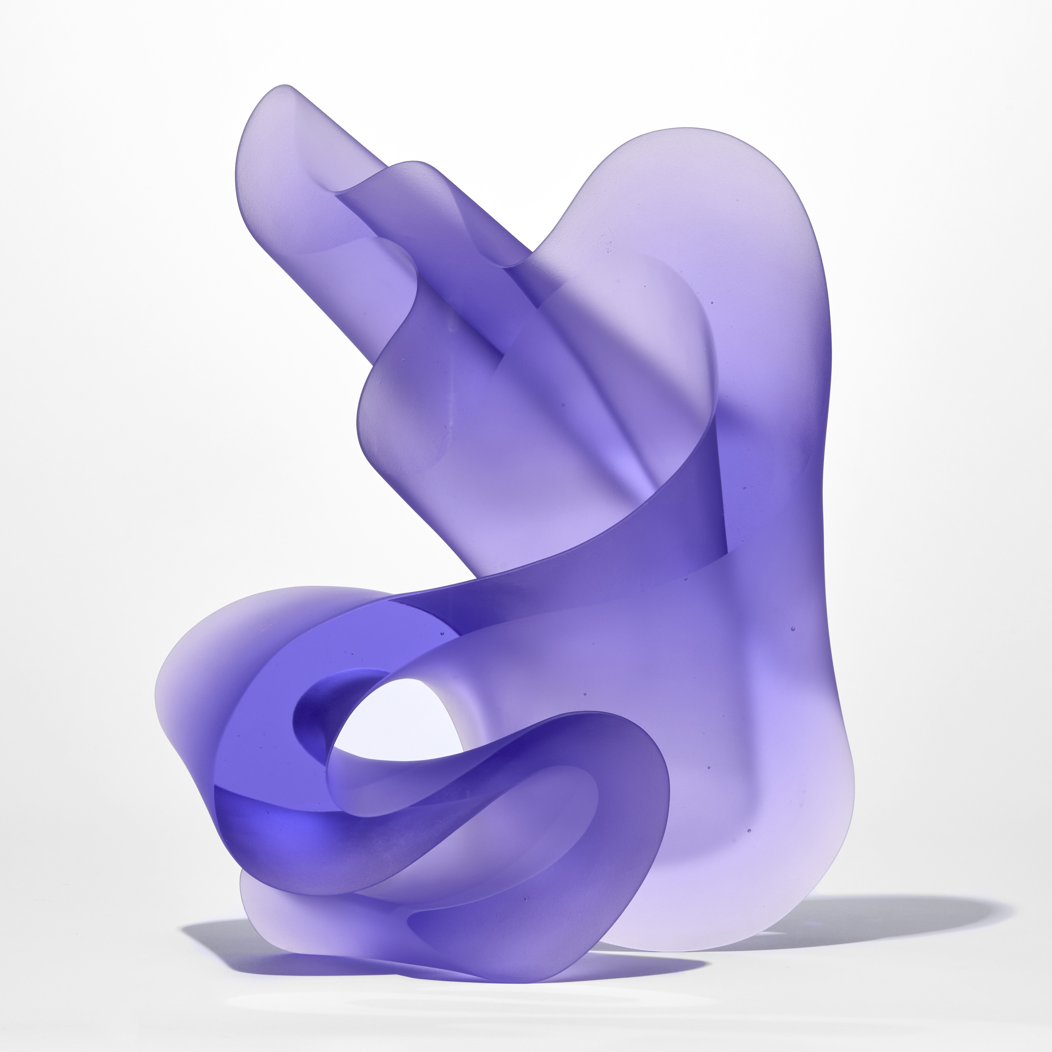 three dimensional standing form with a flat front and back with undulating and curling sides in semi transparent purple hand made from glass