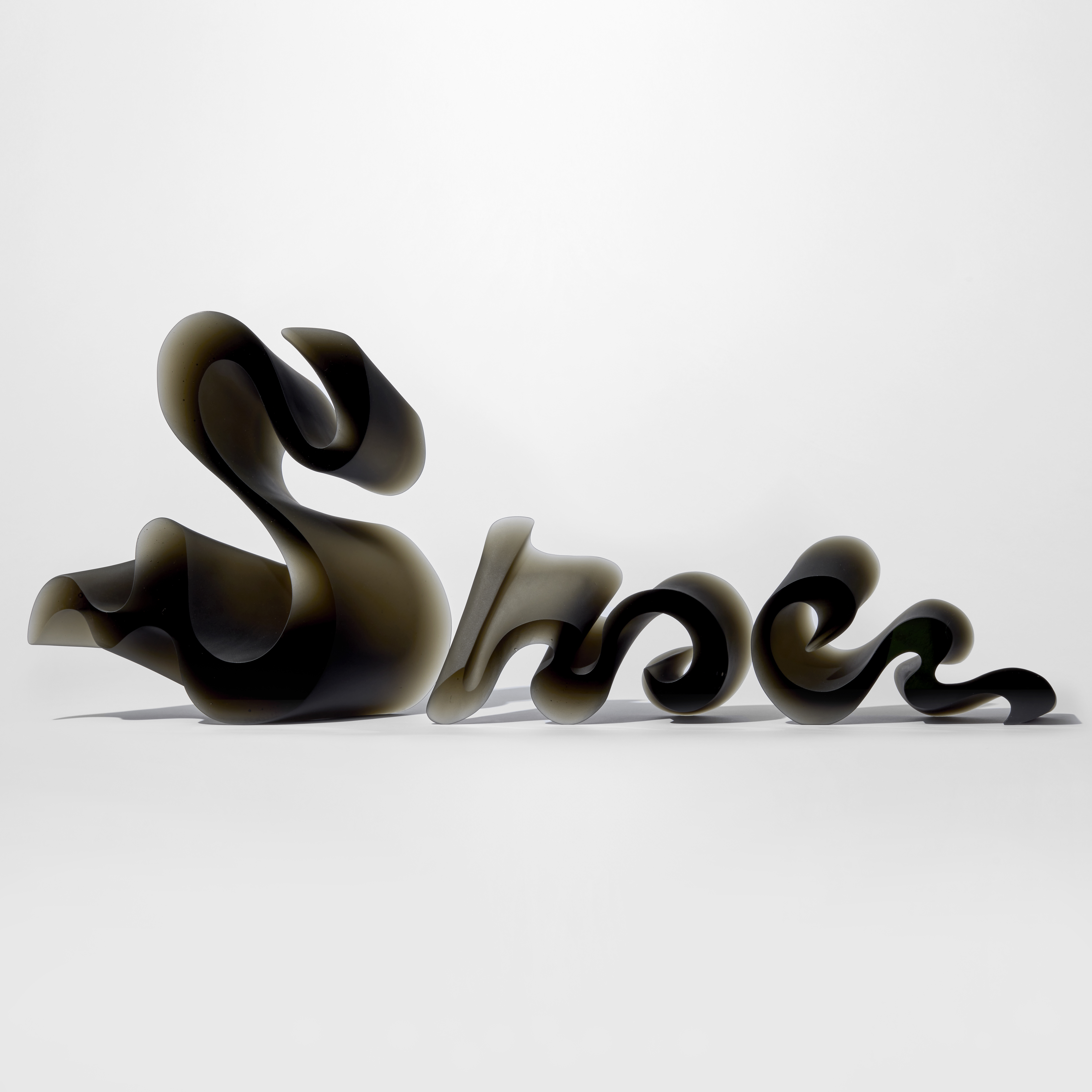 three bronze brown standing semi transparent forms decreasing in size with the appearance of swirls of calligraphy with shiny flat front and back planes with the other sides undulating in curves in differing angles hand made from glass