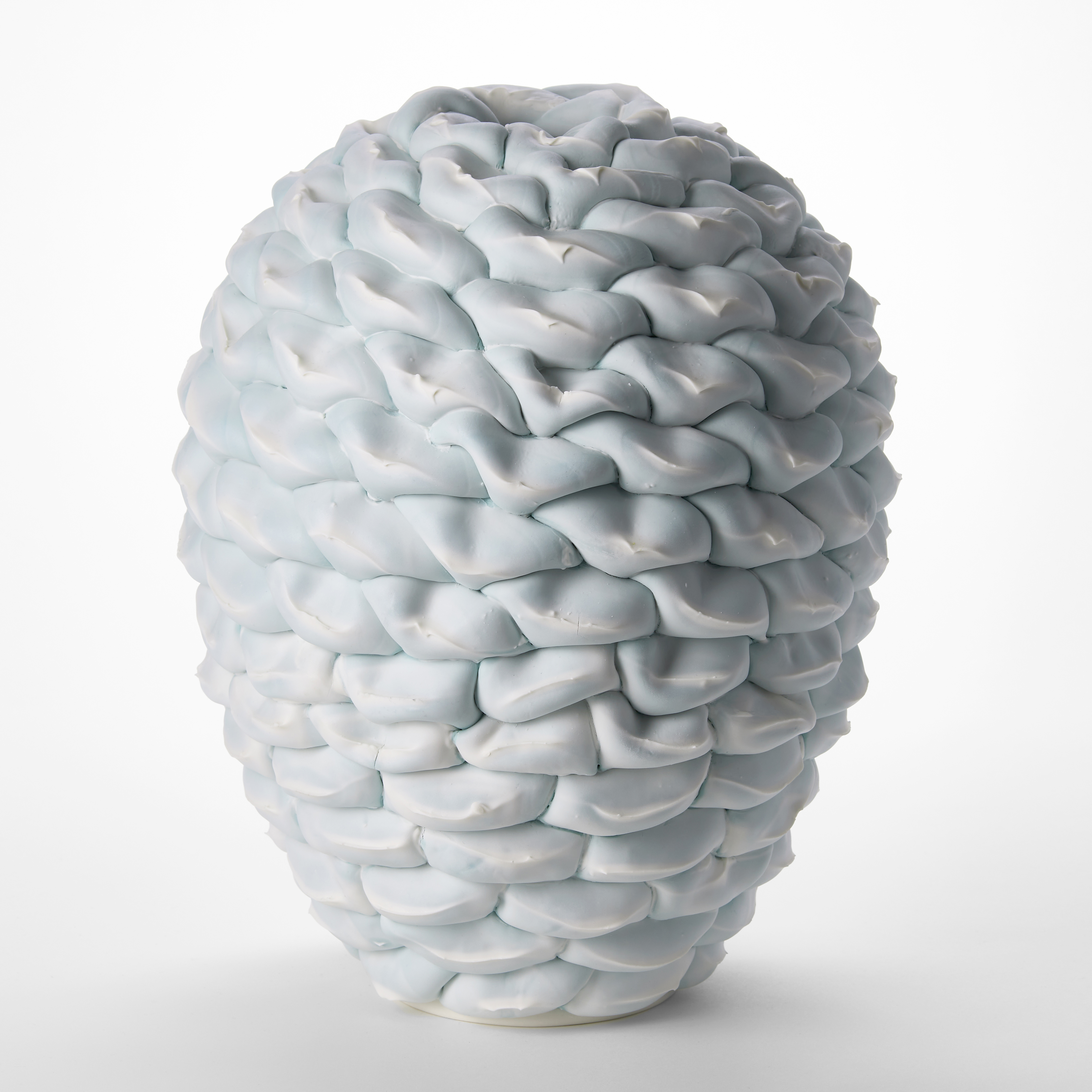 oval standing white and soft celadon turquoise interwoven sculptural vessel with the appearance of a pinecone created from stacked sections hand made from porcelain stoneware and parian